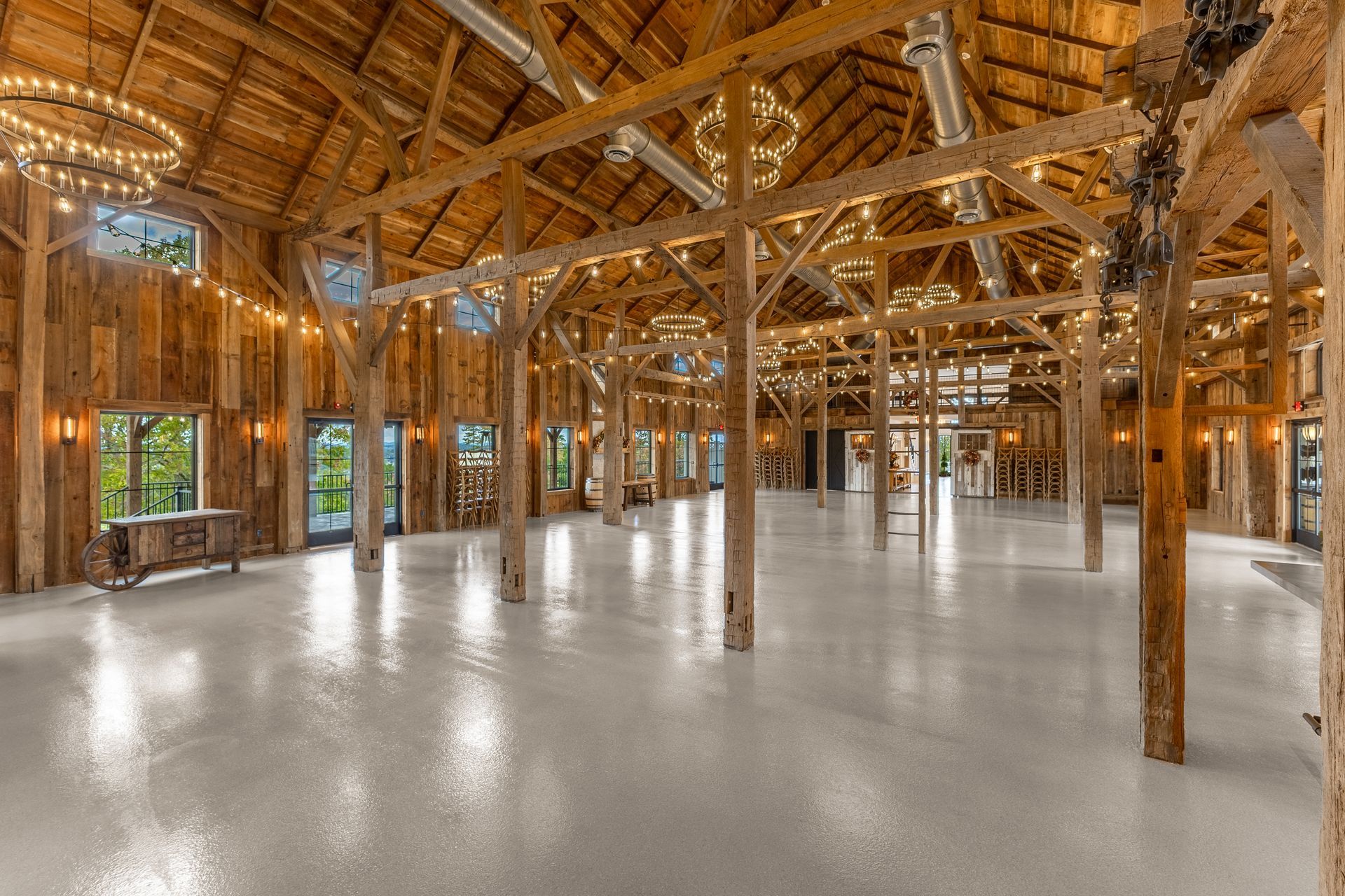 Spacious unfinished timber hall with exposed beams and polished concrete floor, lit by warm sunlight.