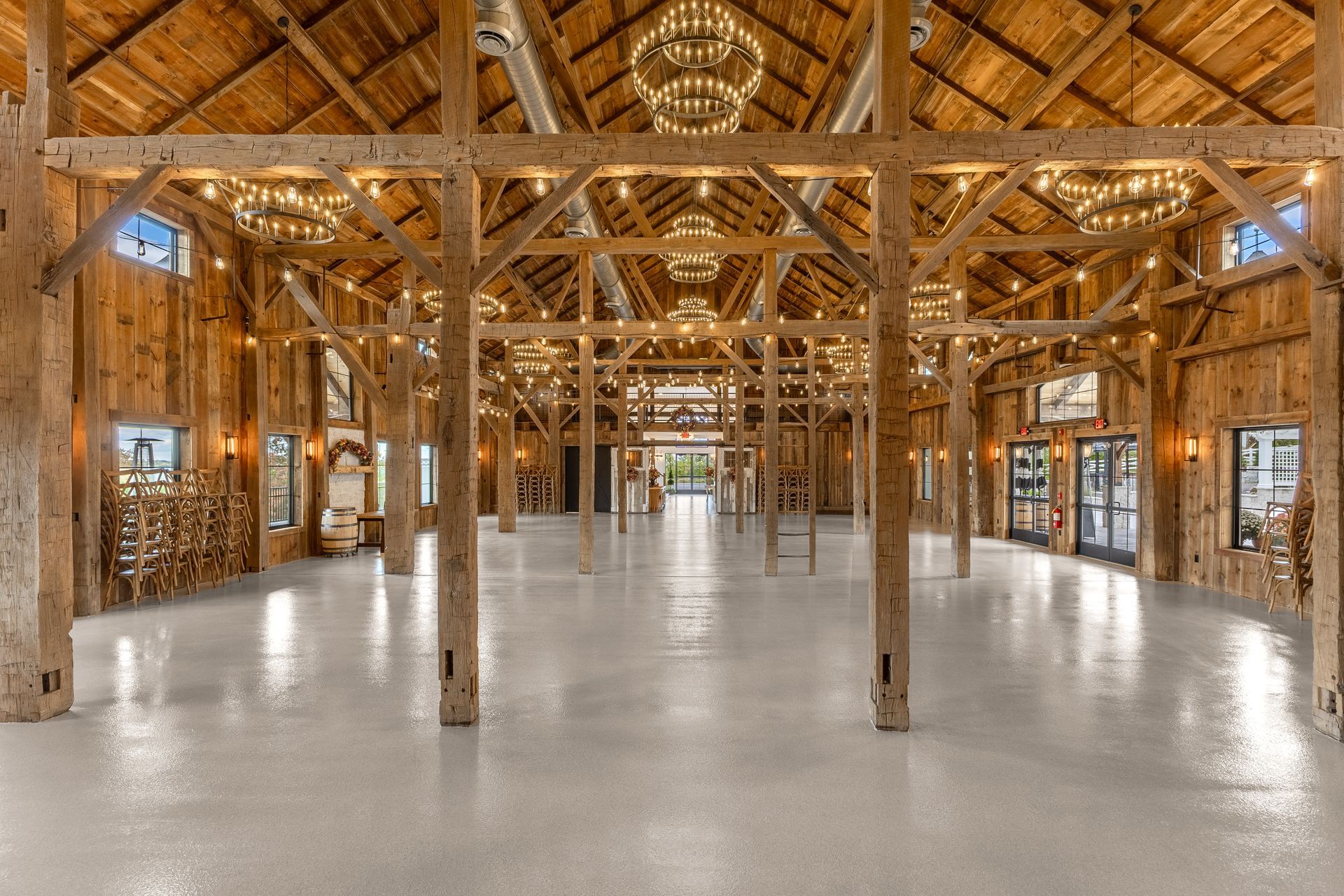Spacious wooden hall with exposed timber beams, chandeliers, and a polished floor