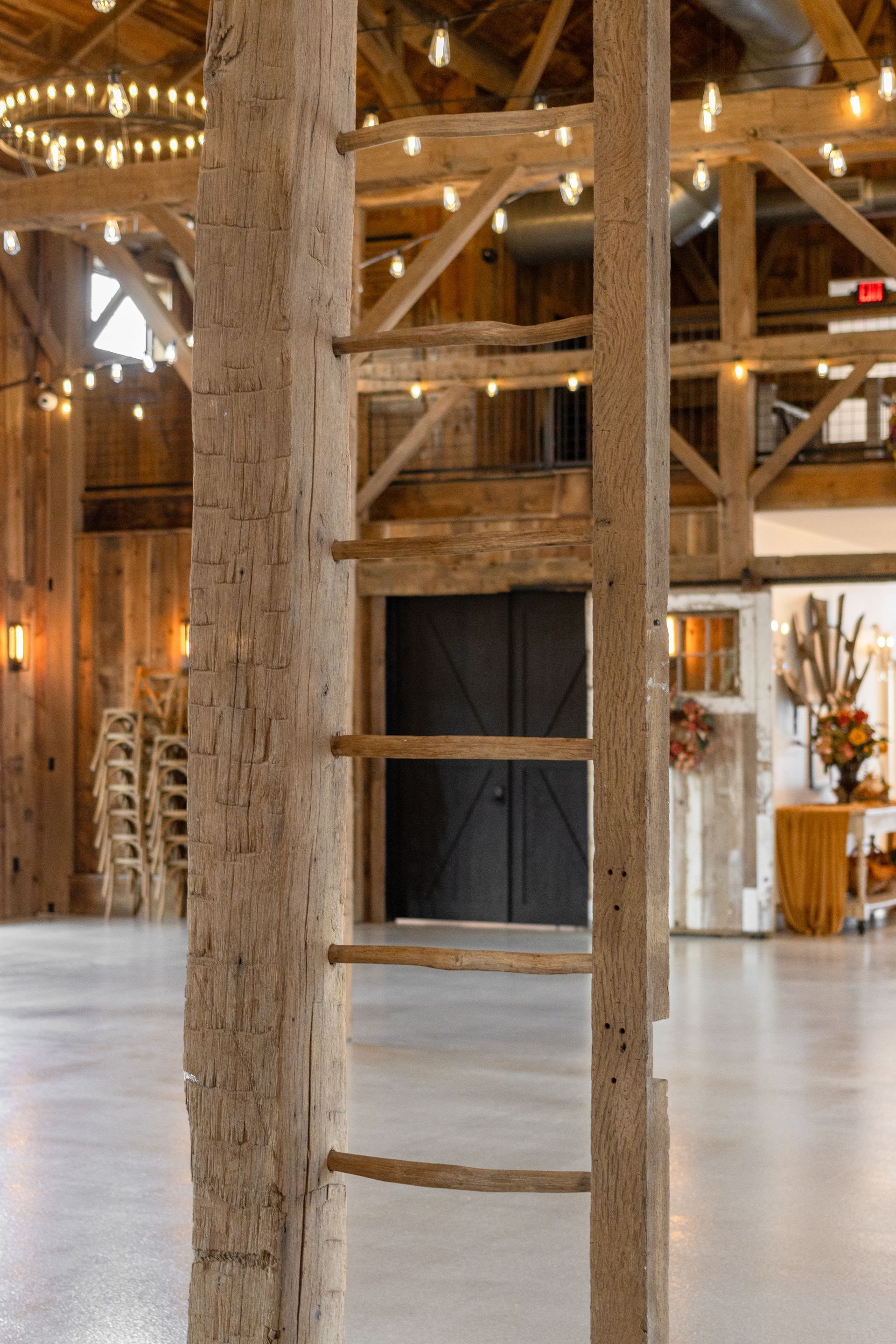 Rustic indoor space with a white wooden ladder and exposed beams in a barn-like hall