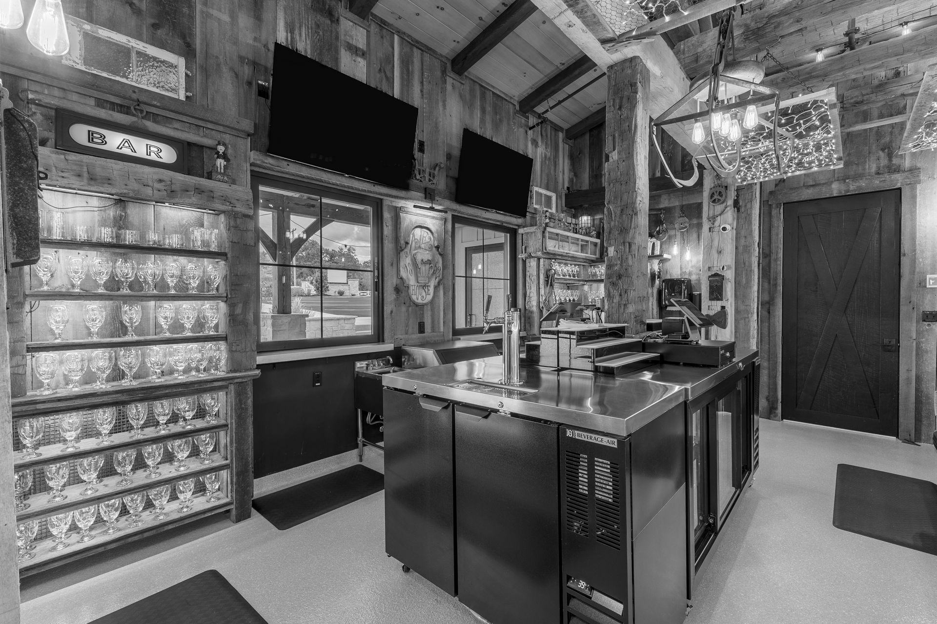 Indoor kitchen with glossy black island, tiled walls, window, shelves, and a closed door.