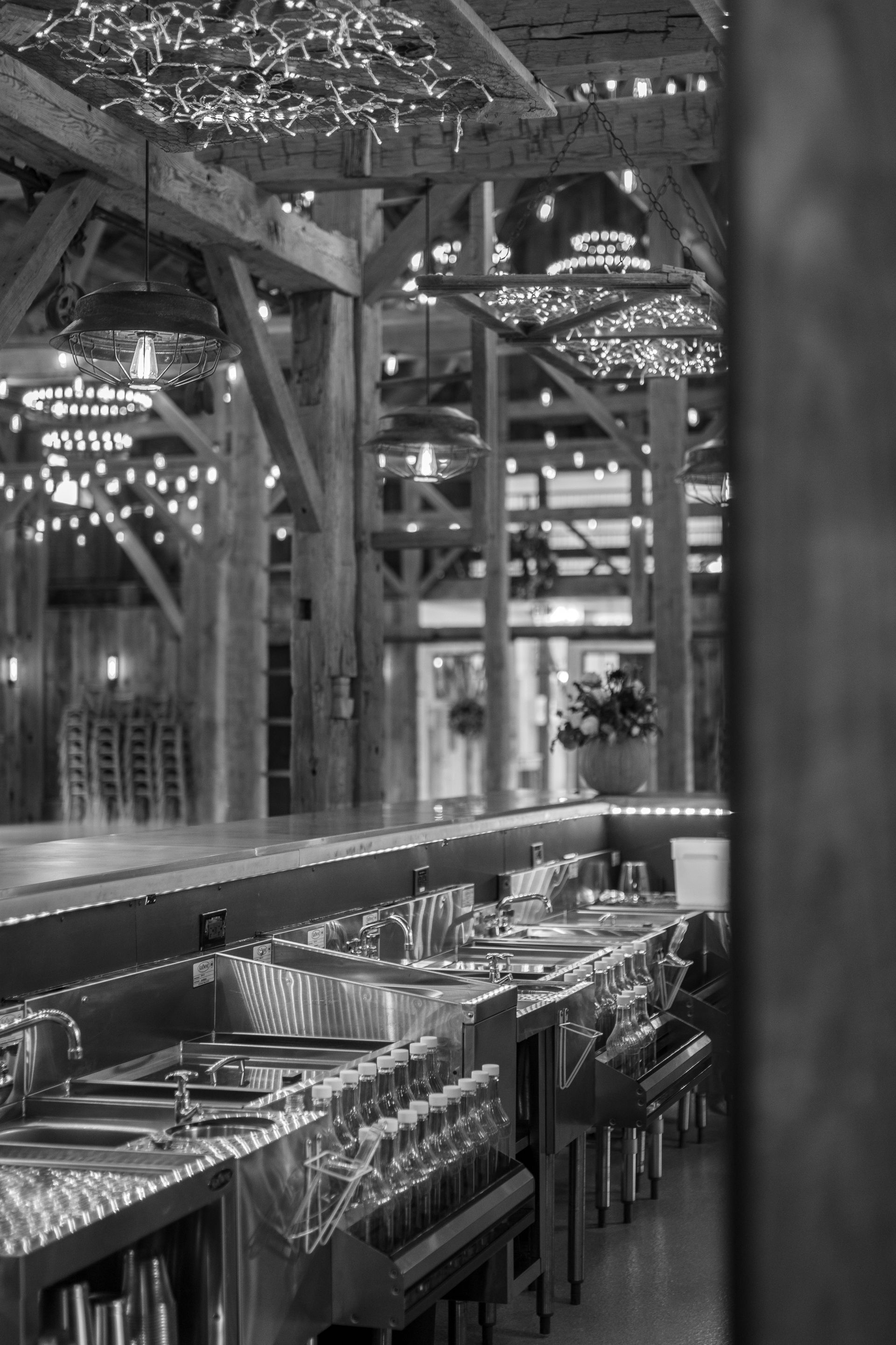 Restaurant patio with wooden tables and chairs under decorative lights and beams