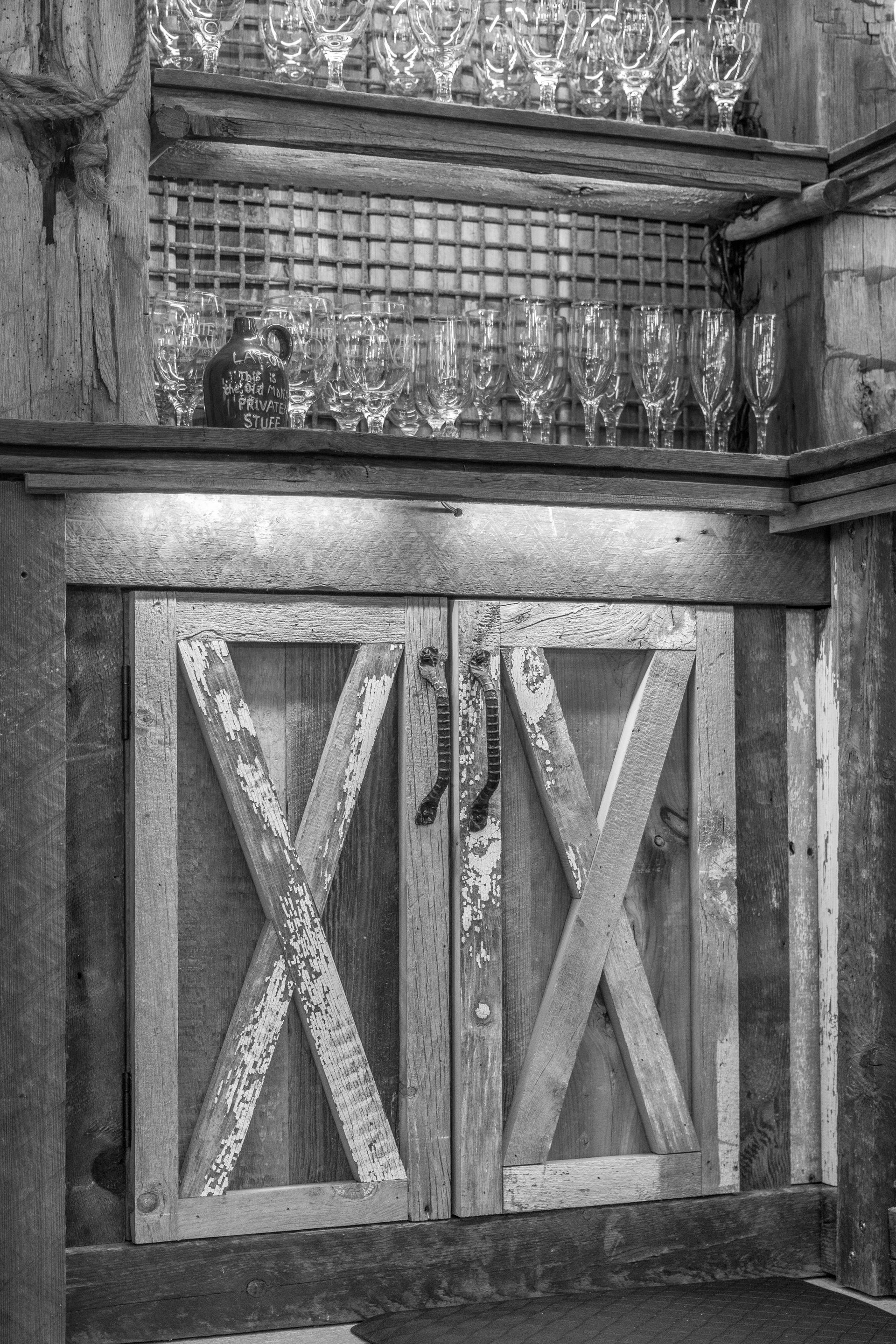 Rustic wooden gate with X-shaped panels and a wire mesh top, set against a wooded background