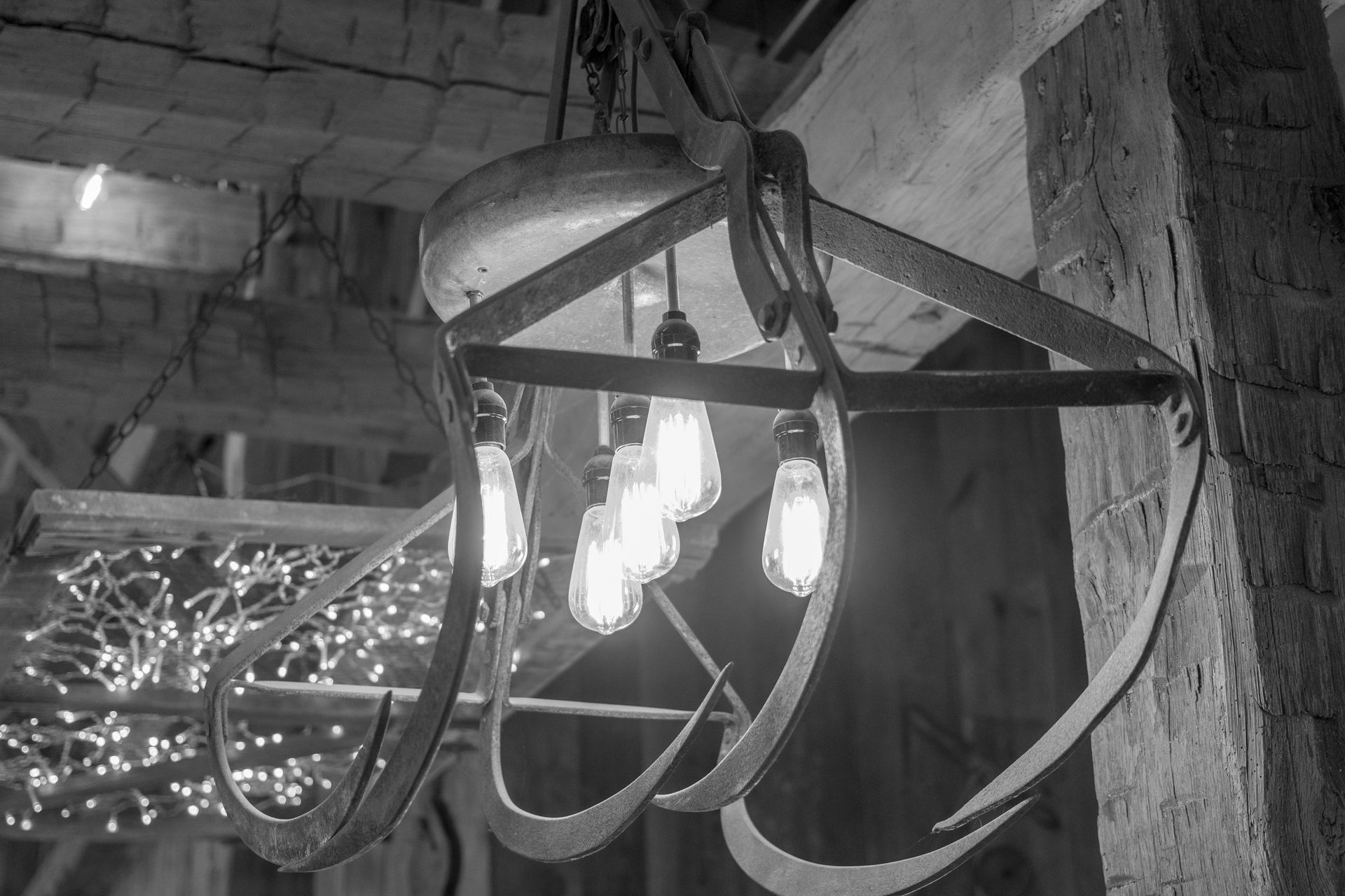 Hanging industrial light fixture with multiple exposed bulbs in a rough concrete interior