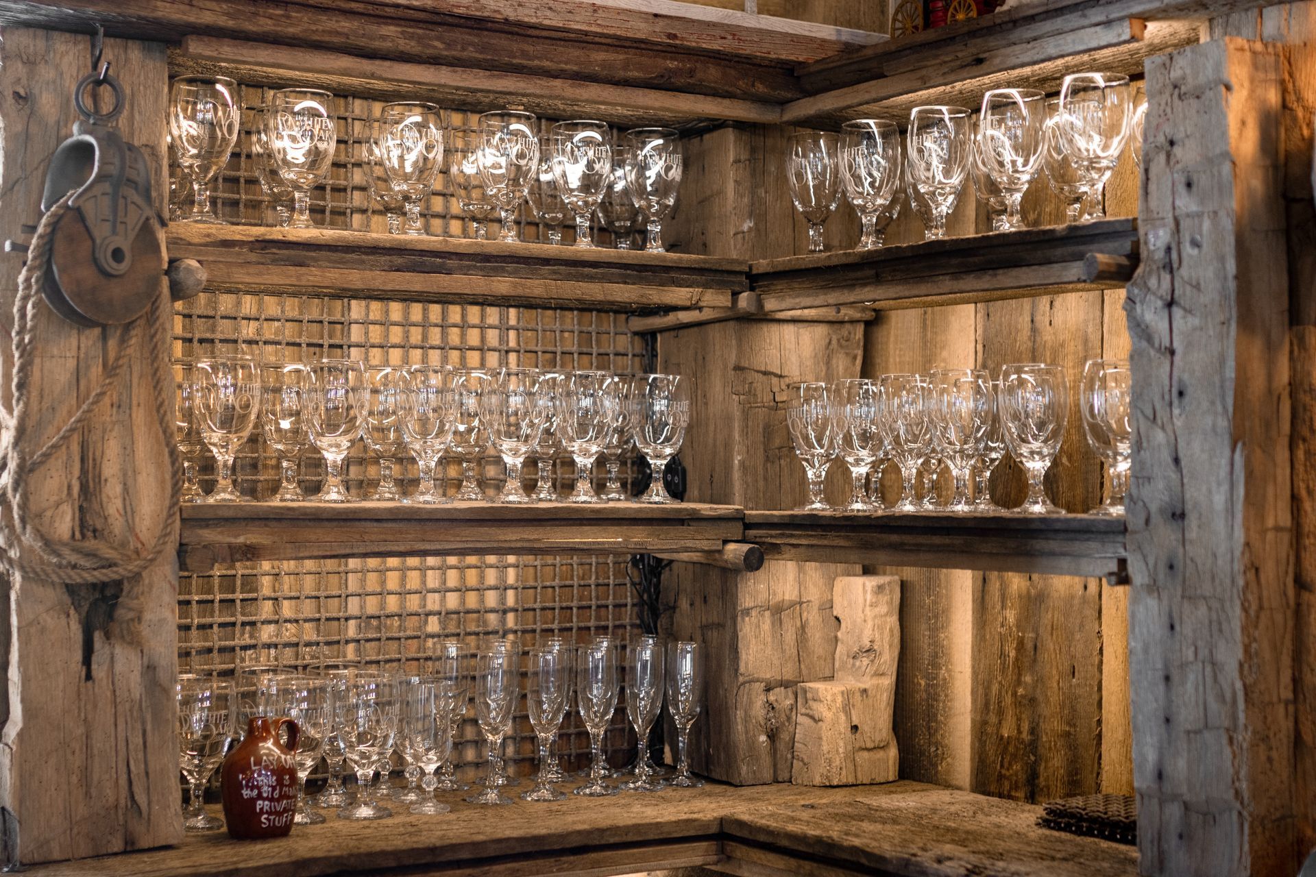 Rustic wooden shelves filled with glassware and bottles in a warm, dimly lit interior