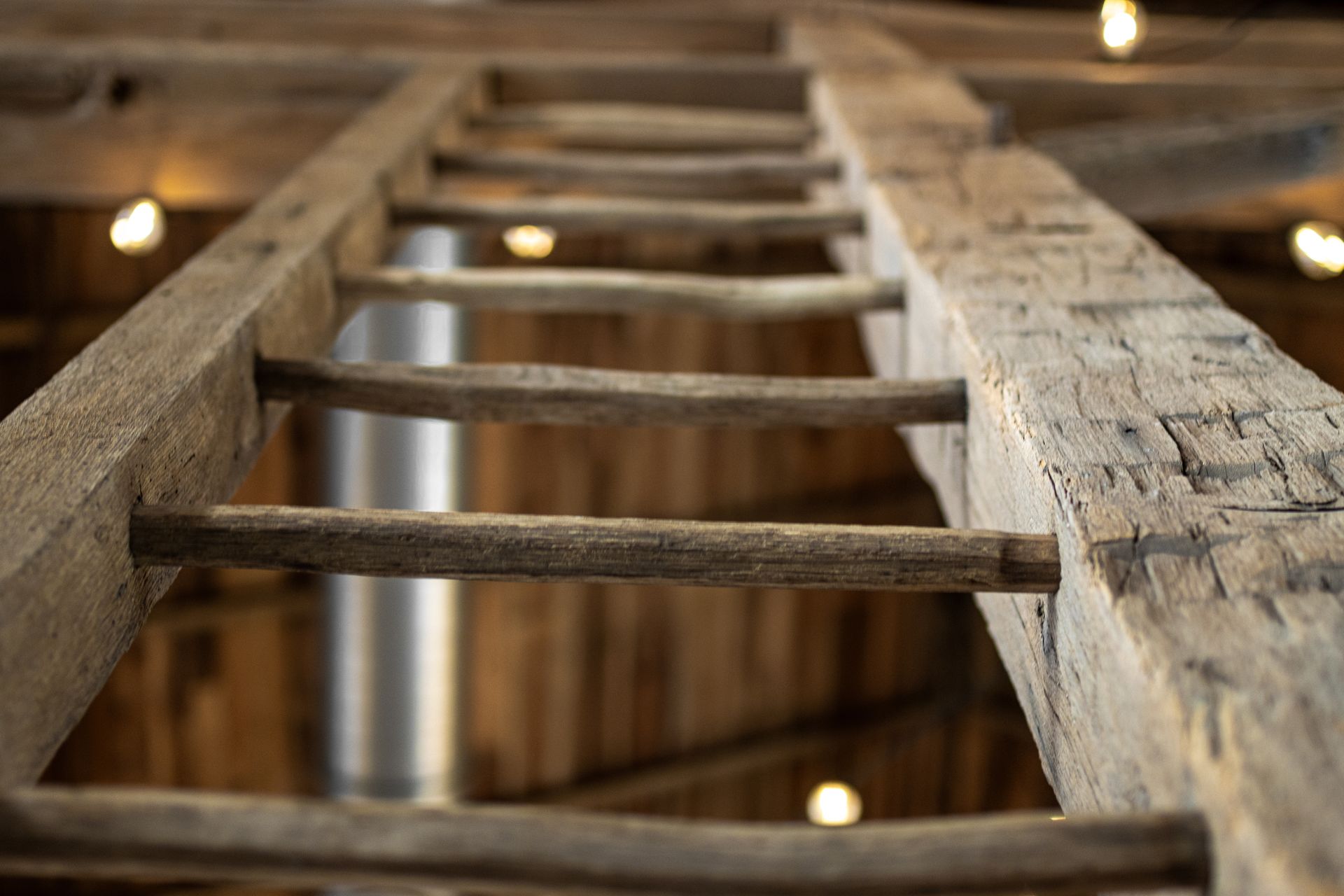 Close-up of a wooden ladder in a rustic attic, viewed from below.