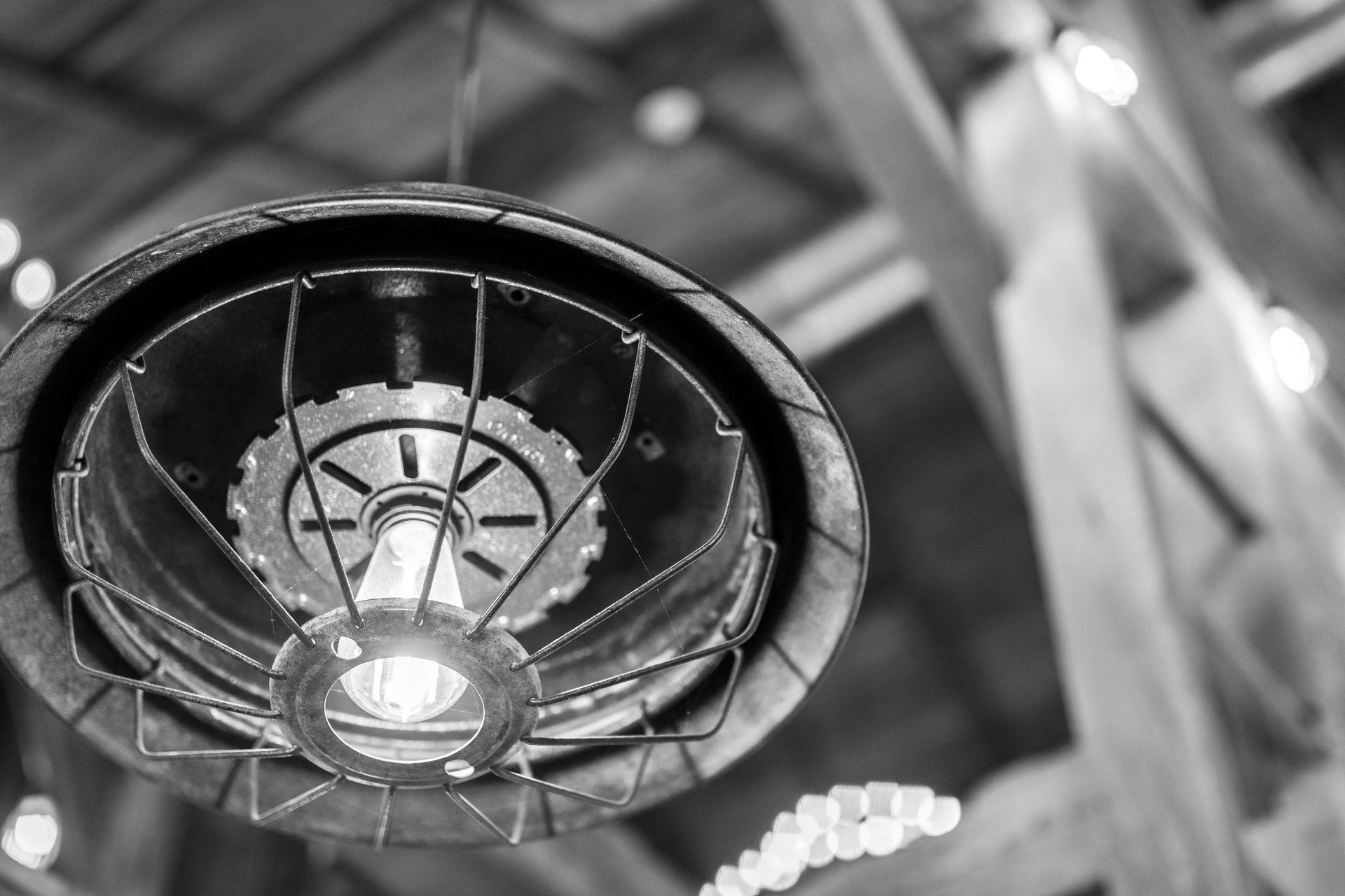 Black-and-white close-up of a glowing vintage ceiling light fixture in an ornate interior