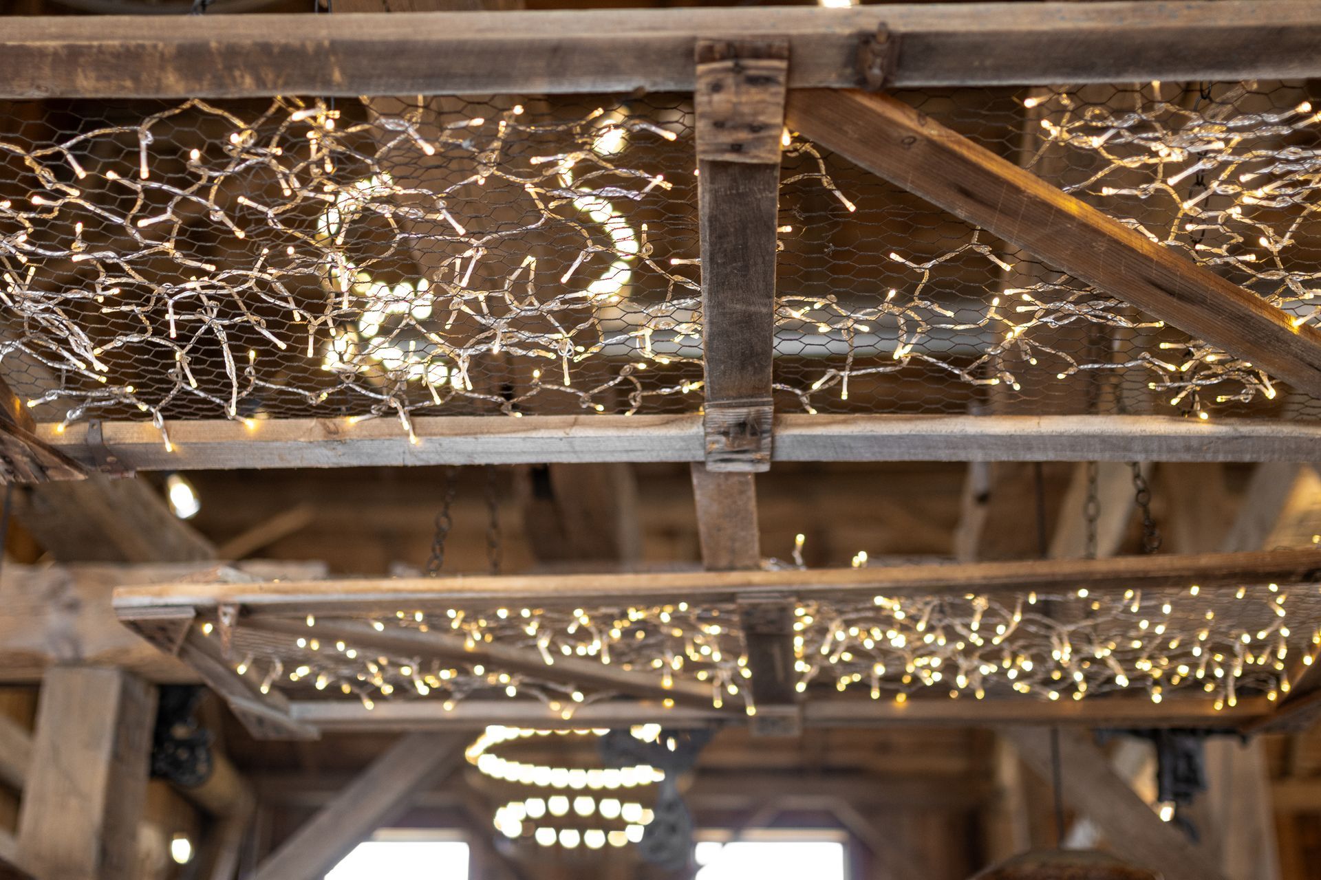 Wooden beams with warm string lights overhead in a rustic indoor setting