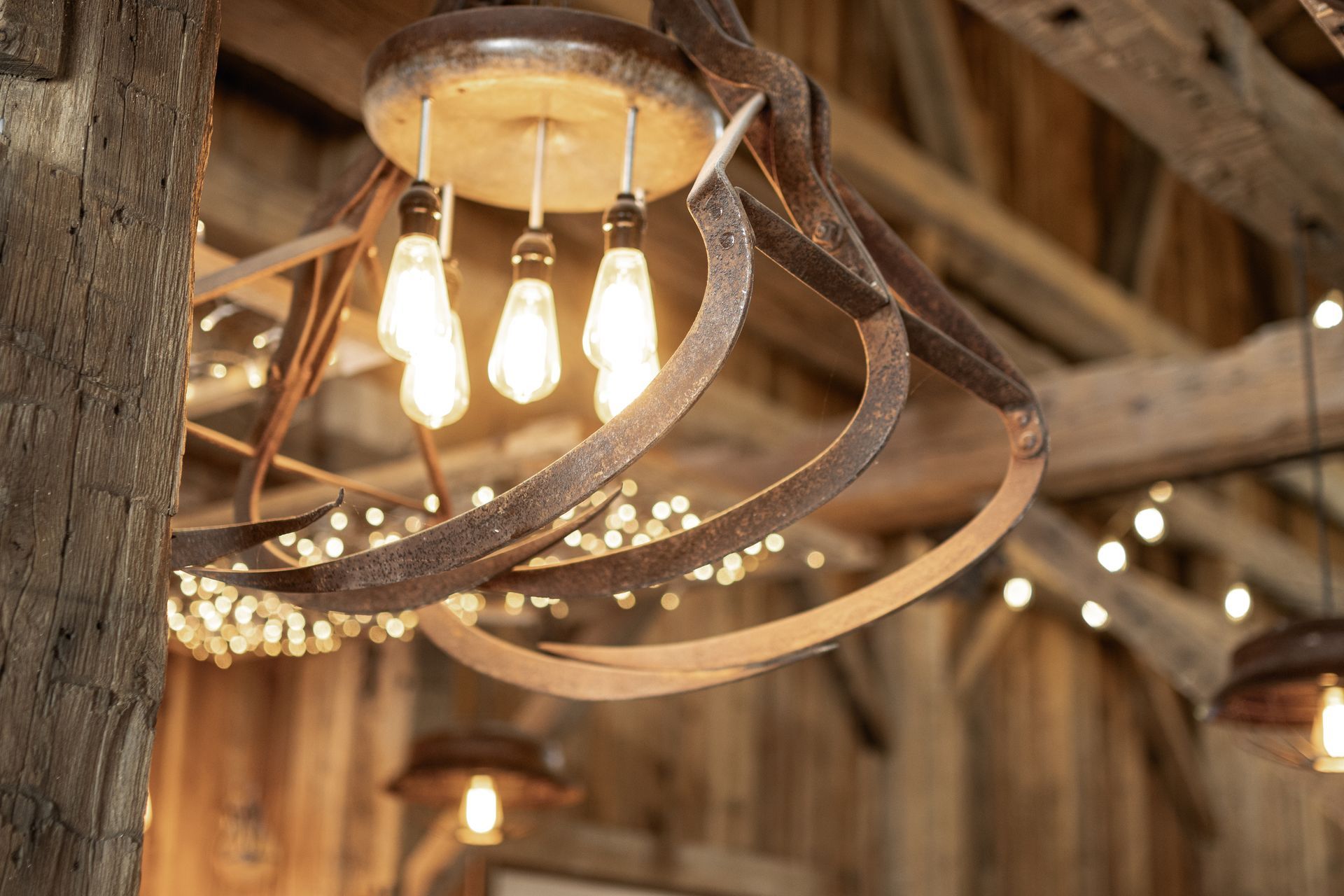 Rustic hanging light fixture with glowing bulbs and curved metal accents in a wooden interior