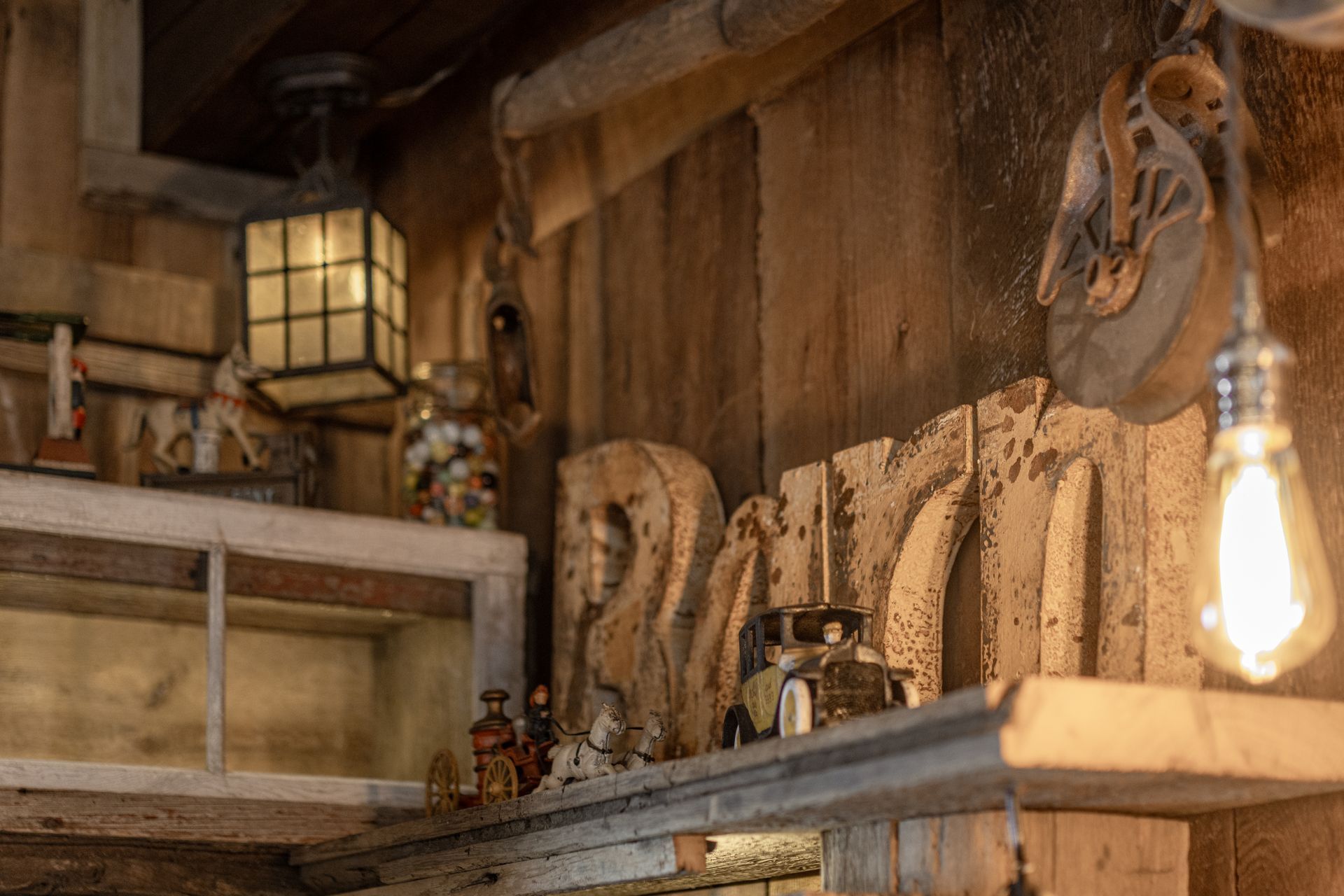 Rustic wooden shelves with carved owl figures, a lantern, and a glowing light bulb in a cozy interior.