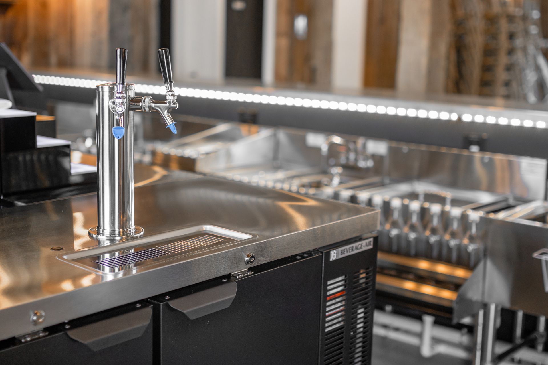 Chrome beer tap at a polished bar counter with glasses and bottles in the background