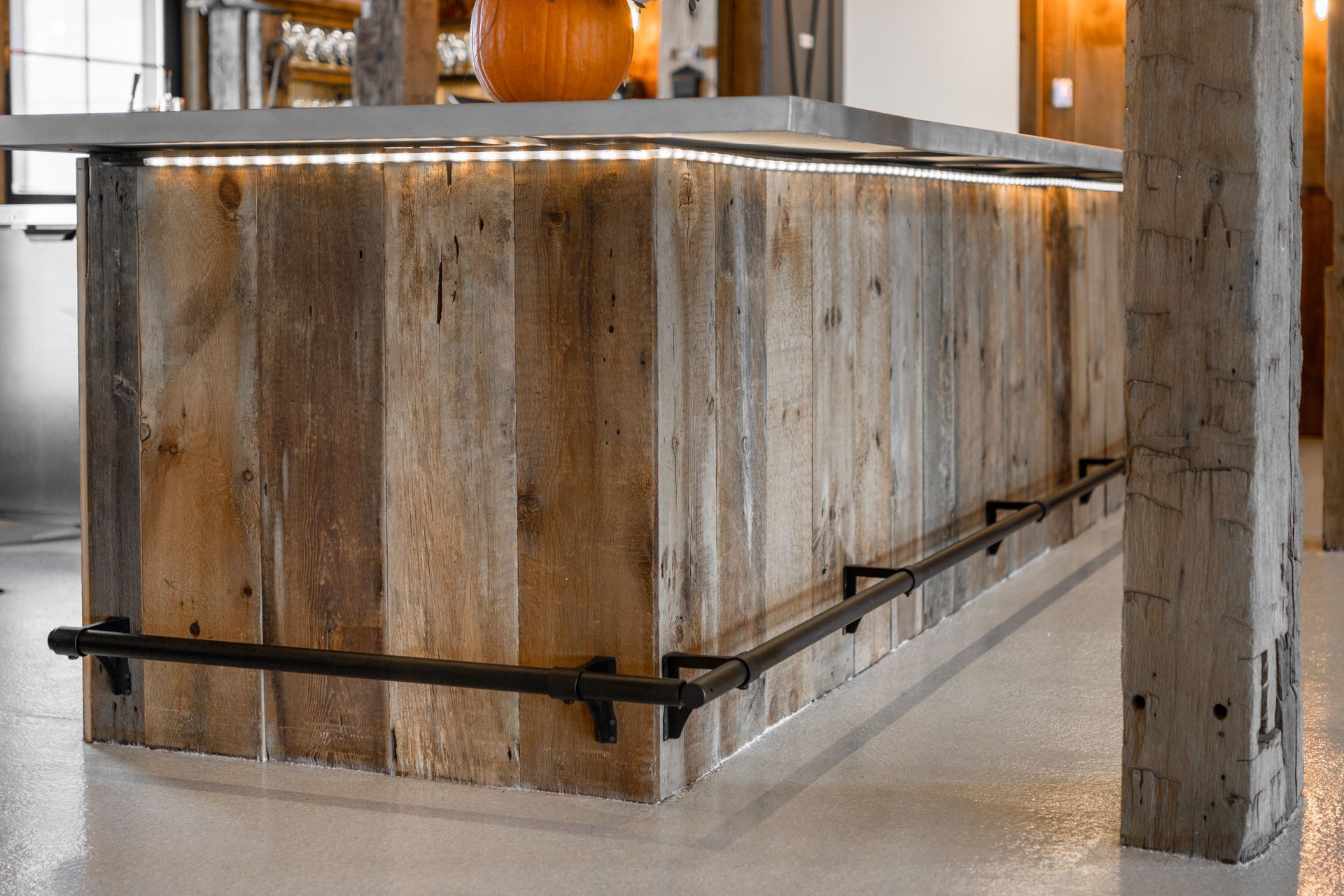 Rustic wooden bar structure with black metal railings in a bright indoor space