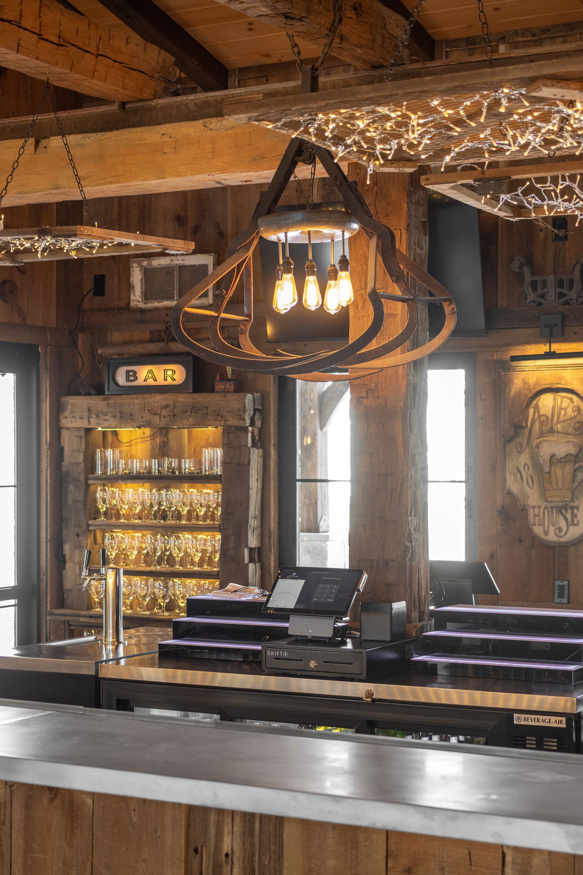 Rustic bar interior with wooden beams, hanging lantern, and glowing lights behind the counter