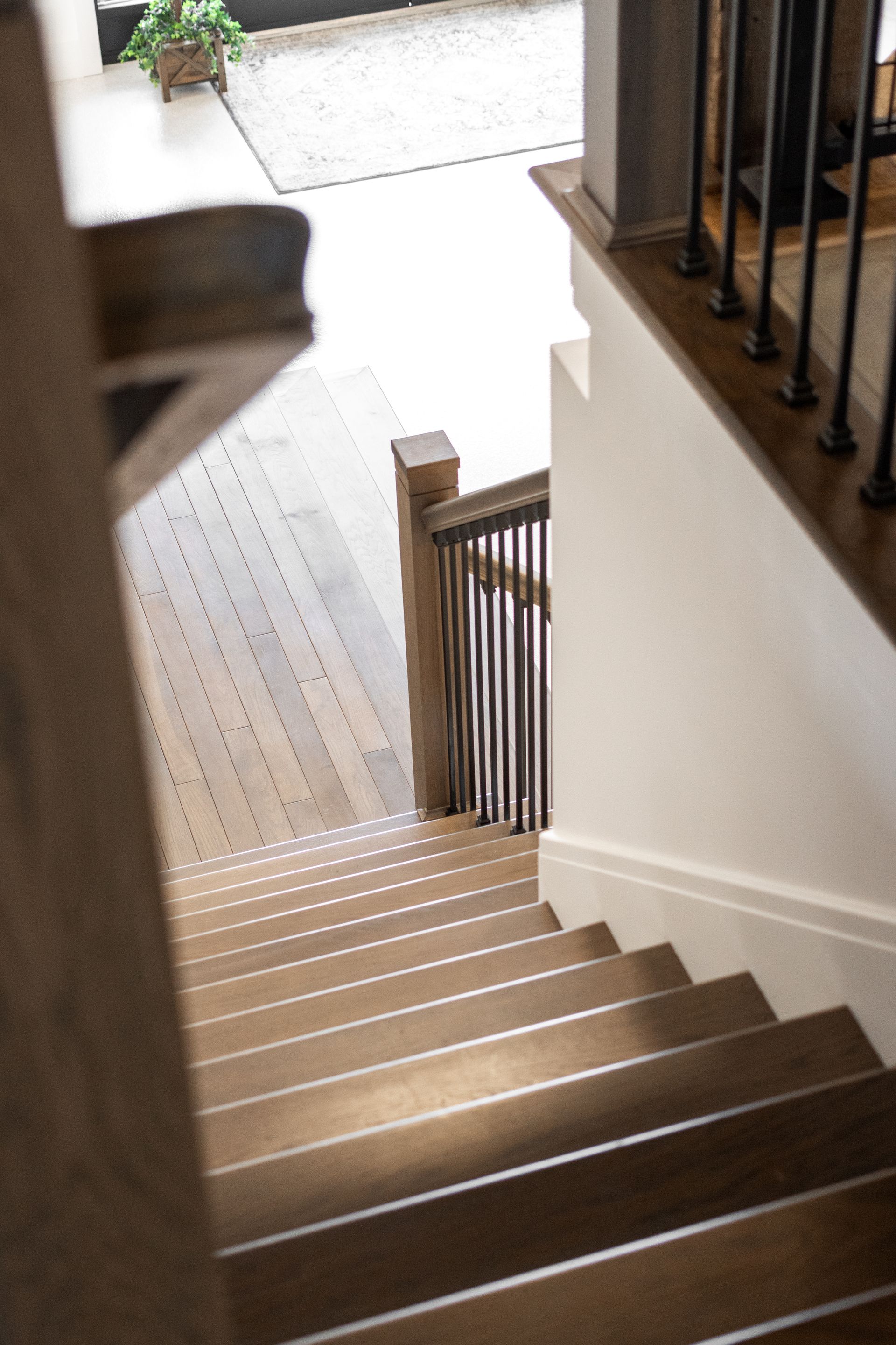 Interior staircase with wooden steps and railing, lit by sunlight from above.