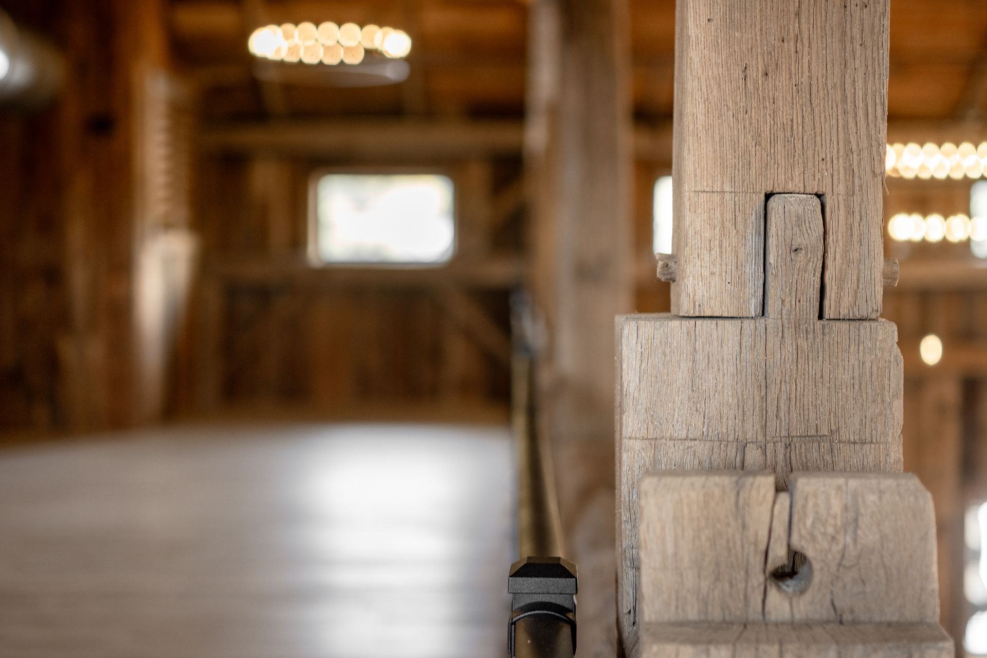 Rustic wooden interior with a close-up of a weathered post in the foreground and blurred lights in the background