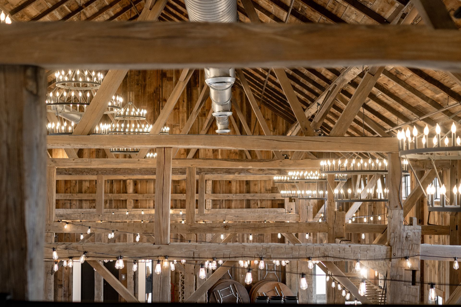 Interior of a rustic wooden barn with exposed beams and sunlight filtering through the roof
