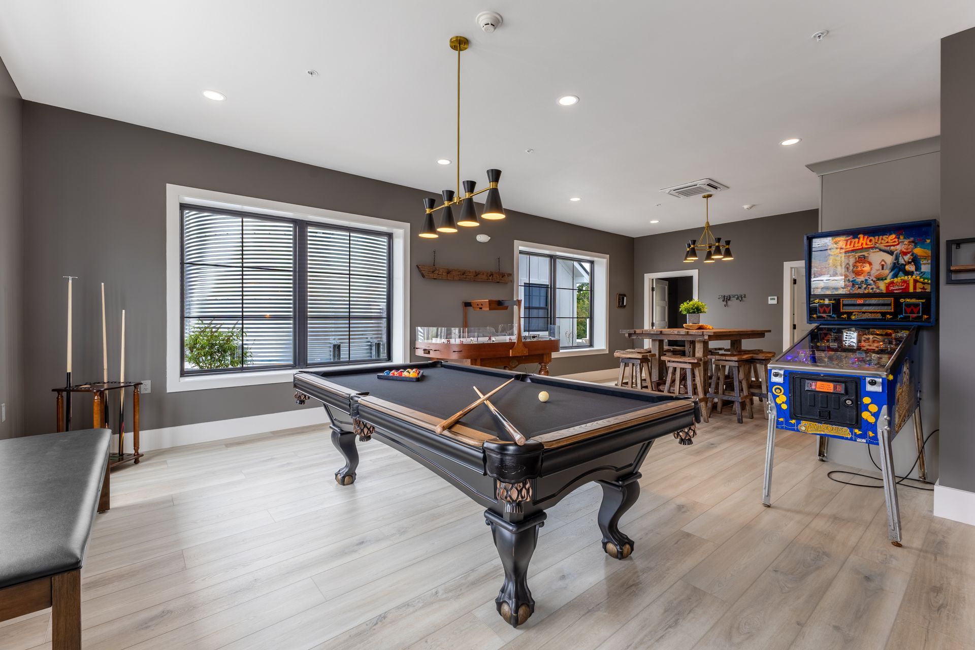 Modern game room with pool table, arcade machine, large windows, and bar seating