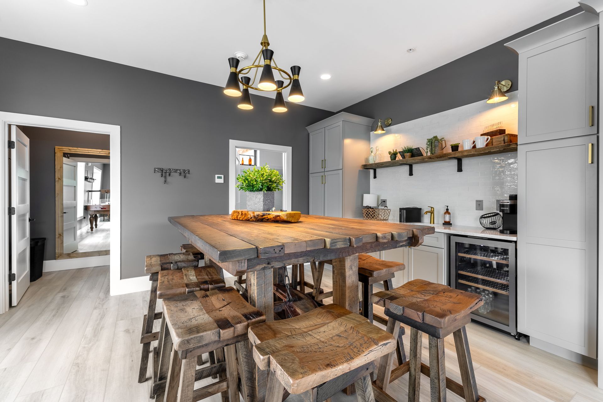 Modern kitchen with rustic wood island, stools, black chandelier, and gray cabinets