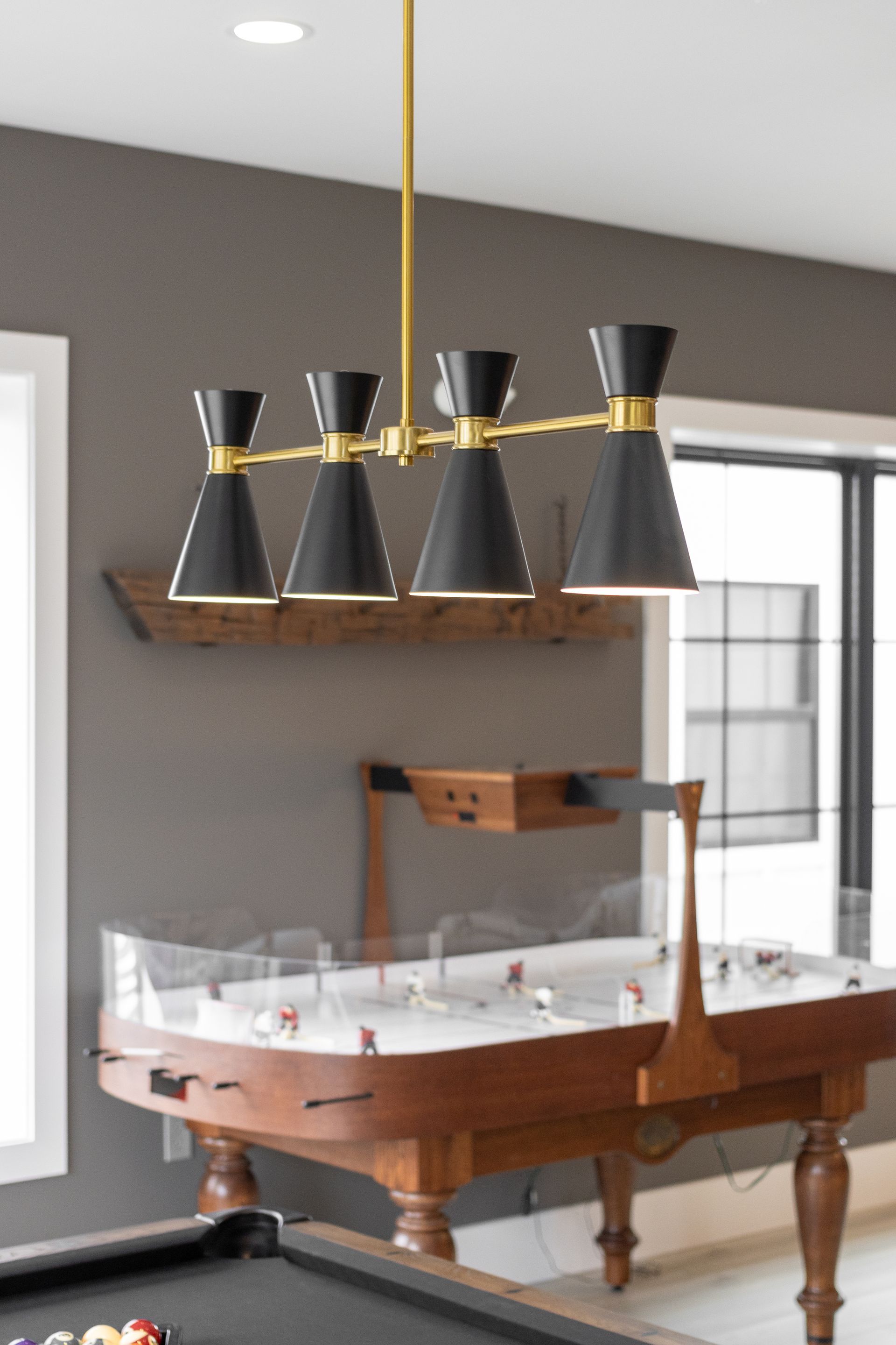 Modern game room with a wooden pool table and black pendant lights in a bright interior