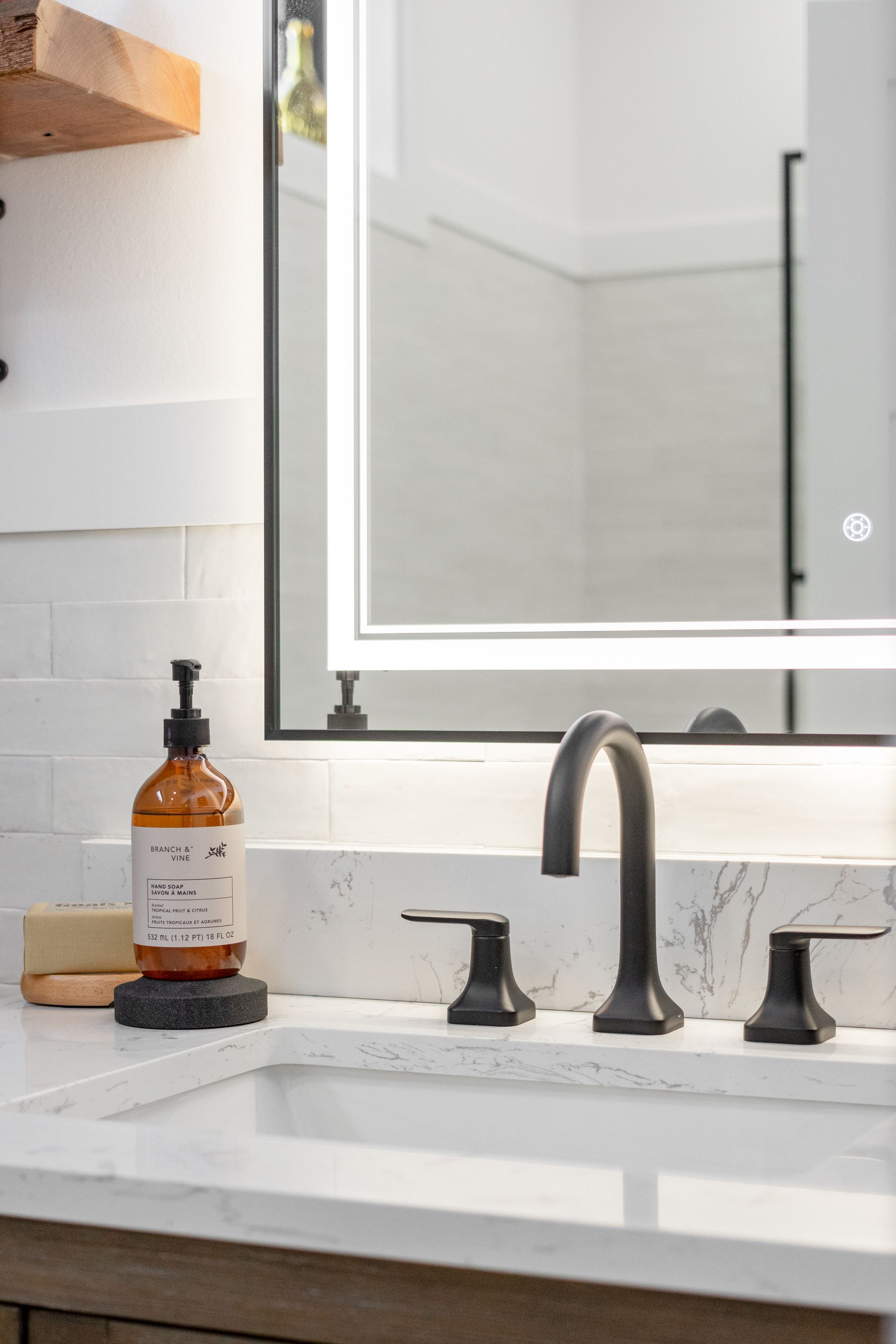 Modern bathroom vanity with white sink, black faucet, mirror, and soap dispenser on the counter