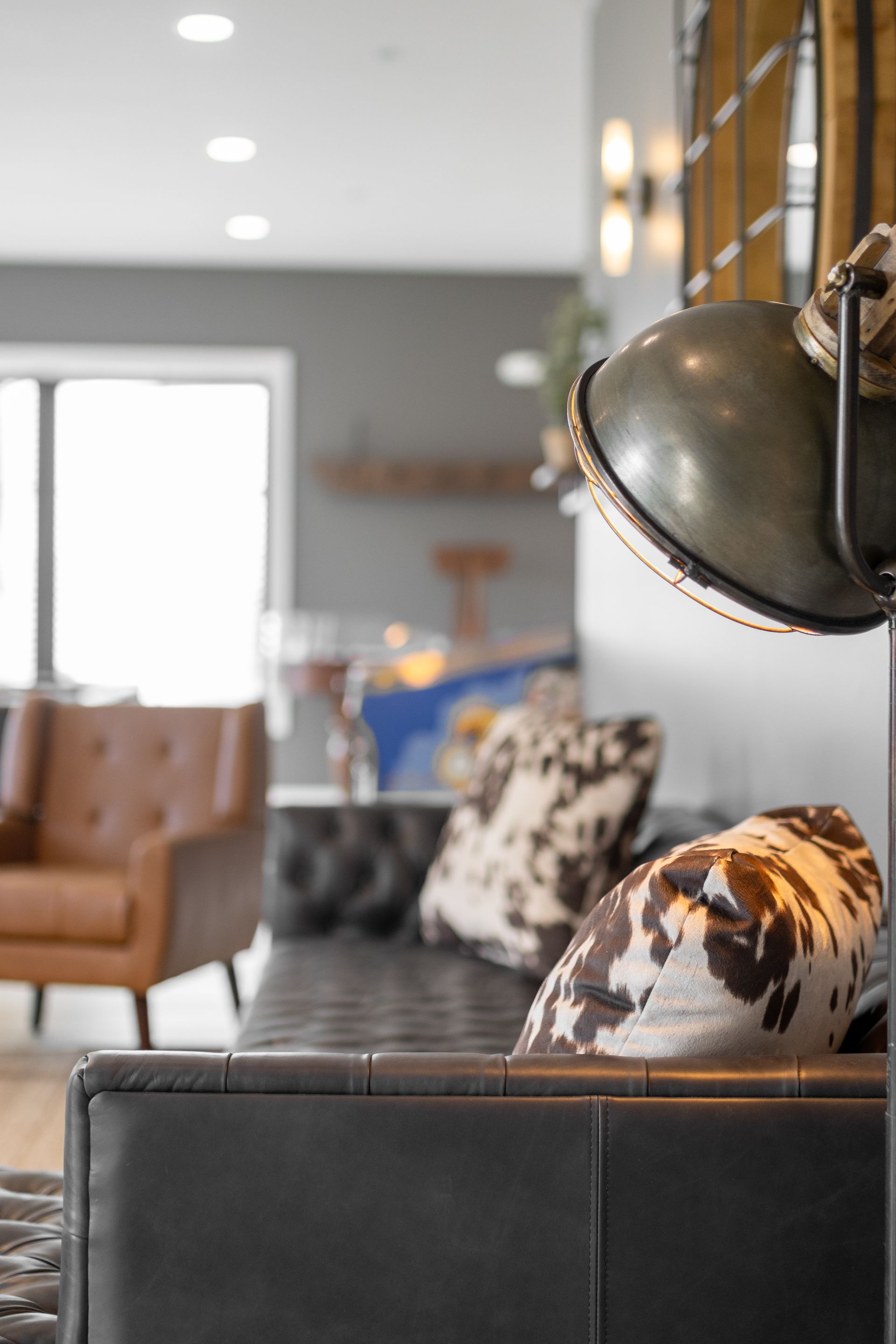 Modern living room with black leather sofa, patterned pillows, and a large floor lamp.