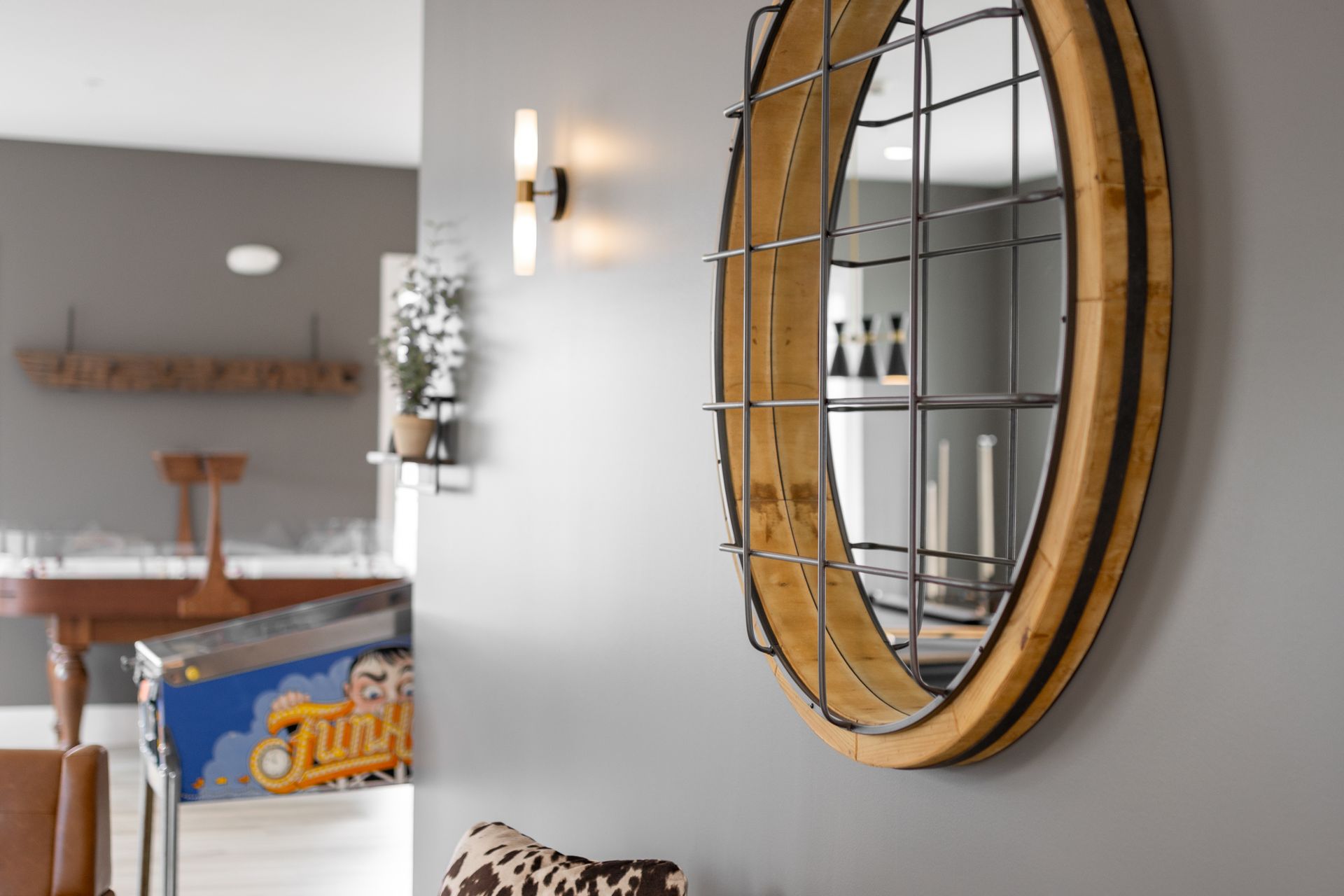 Modern living room with a round gold-framed wall mirror and a wooden table in the background