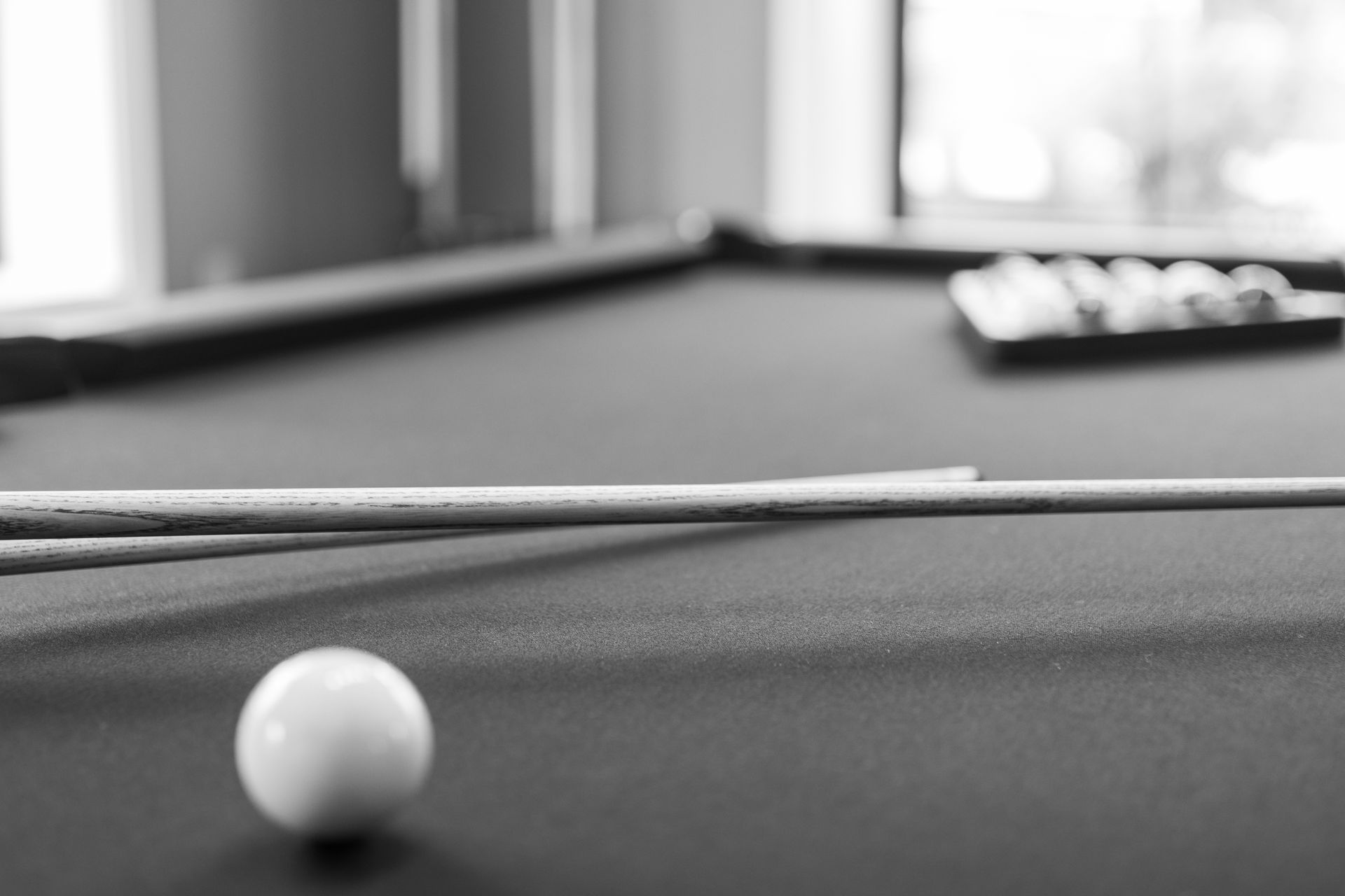 Black-and-white pool table with a white cue ball in the foreground and blurred balls at the far end