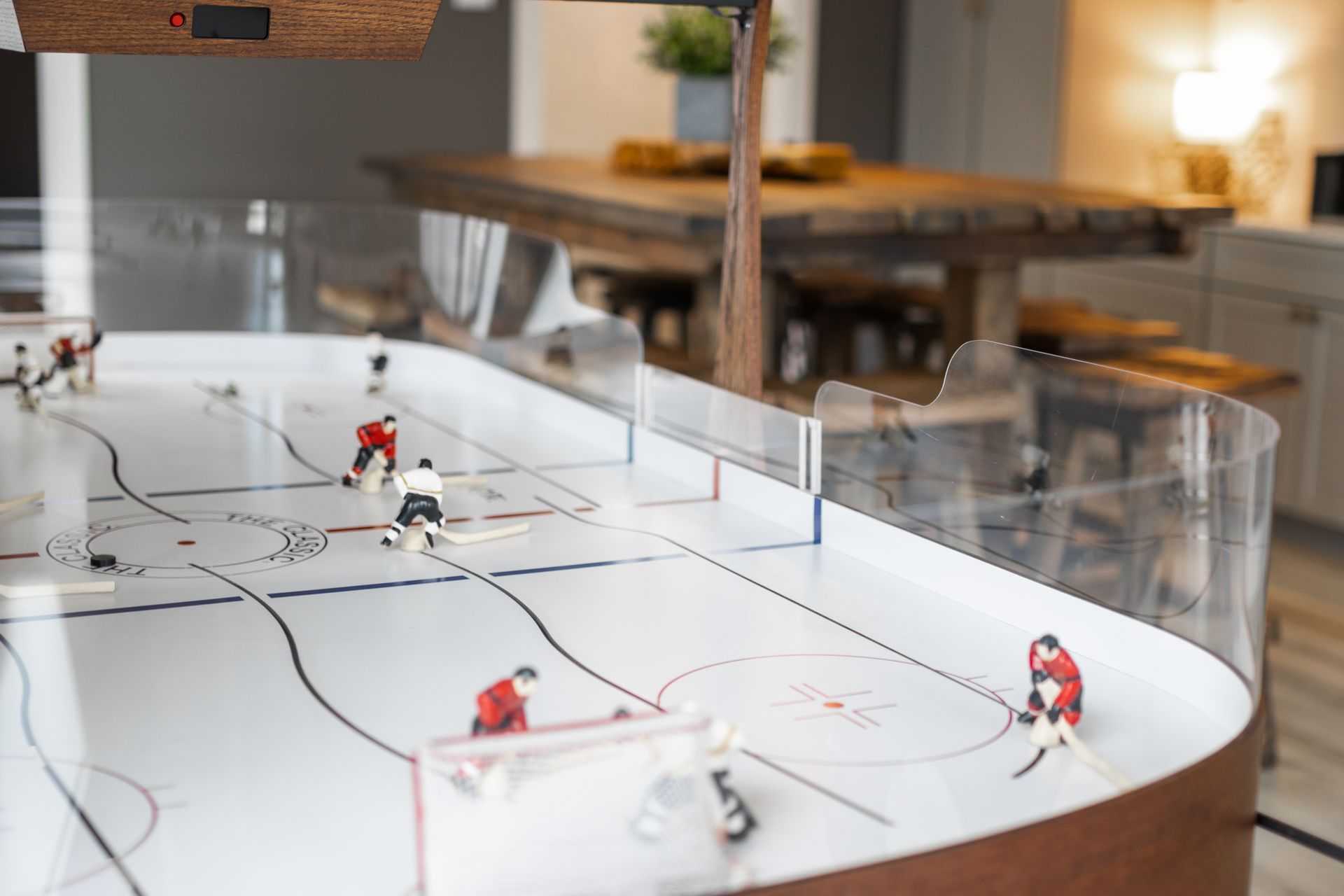 Miniature hockey rink with small players and clear boards on a table in a cozy room