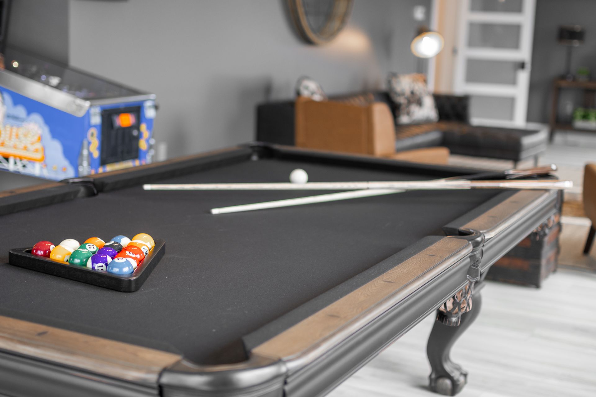 Black pool table with balls and cues in a living room