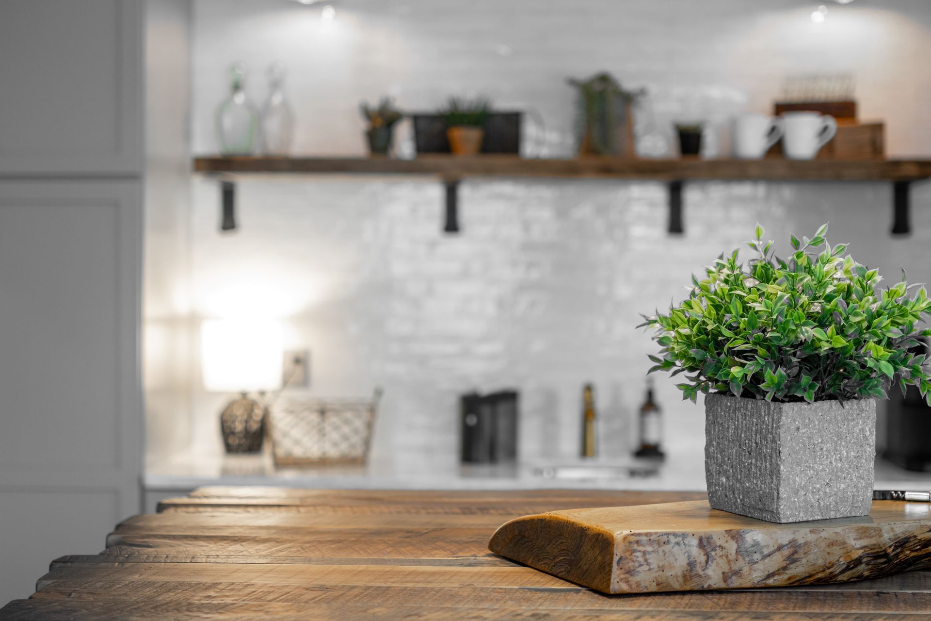 Potted green plant on a wooden table in a bright, blurred kitchen interior