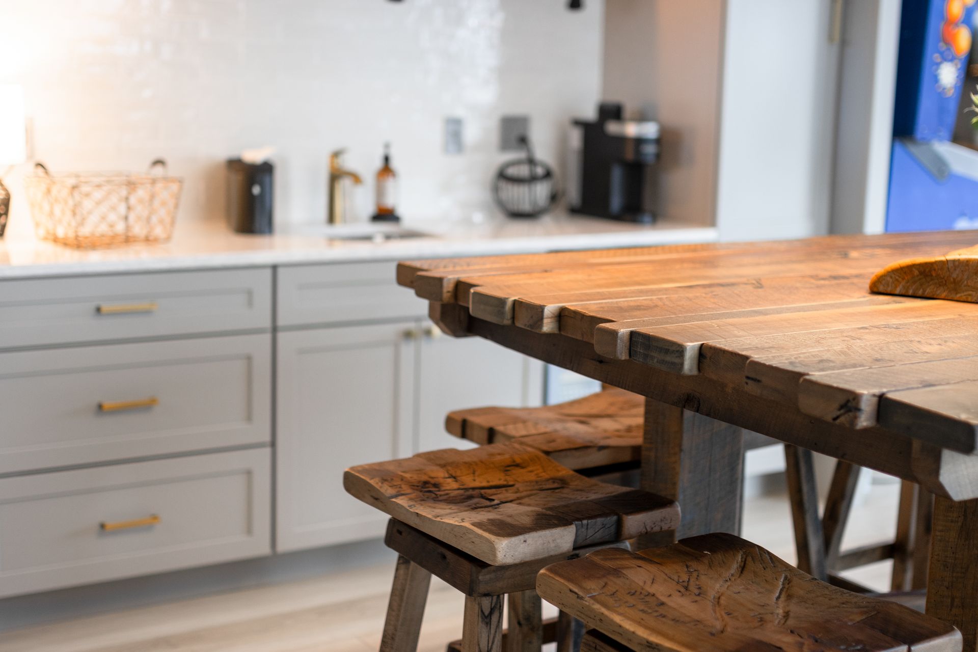Rustic wooden table in a bright kitchen with white cabinets and a coffee machine on the counter