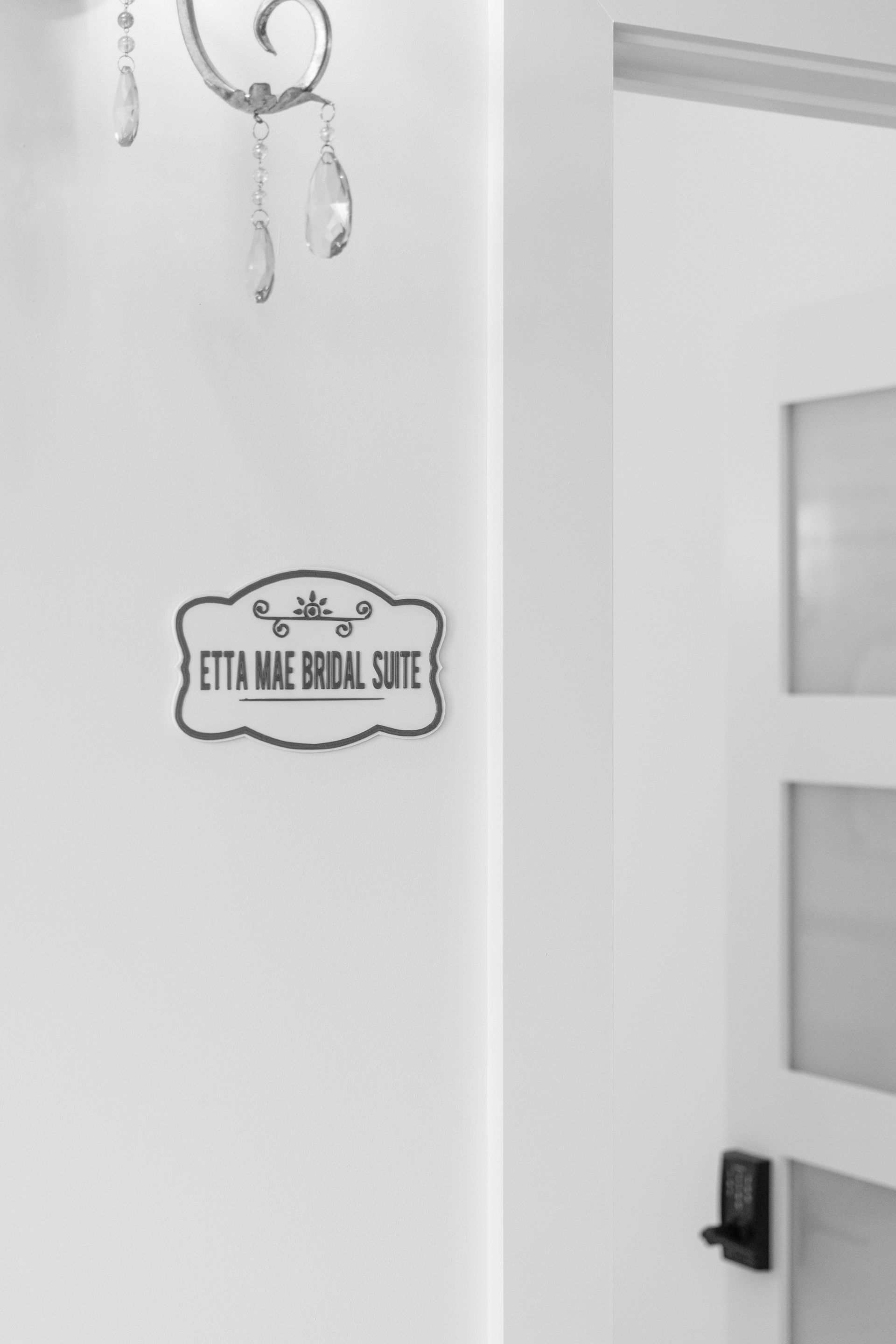 White wall with a small decorative sign beside a partially open door.