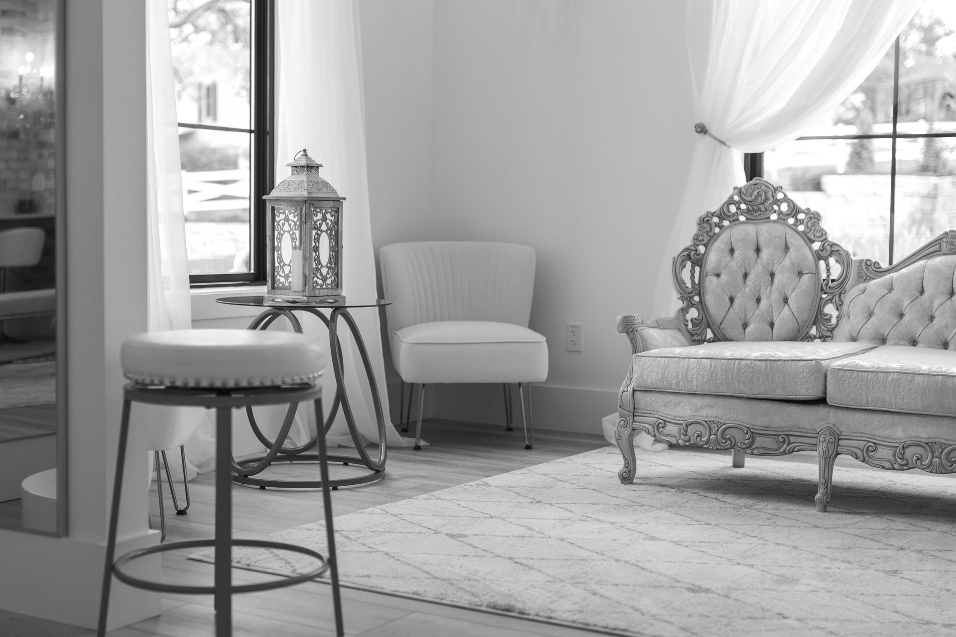 Elegant living room with ornate sofa, chair, stool, and lamp in soft natural light