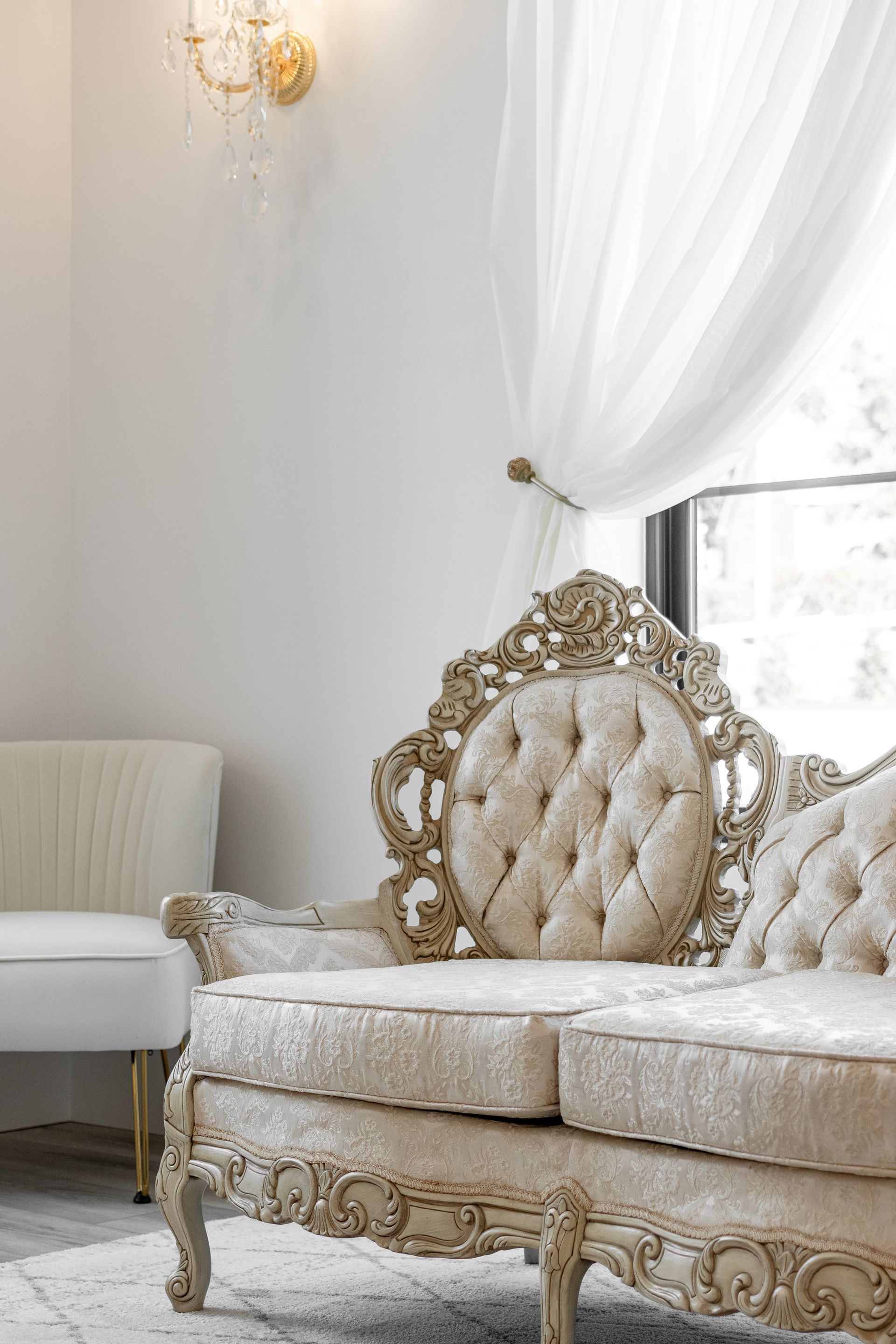 Elegant white and gold ornate sofa in a bright, airy living room by a window