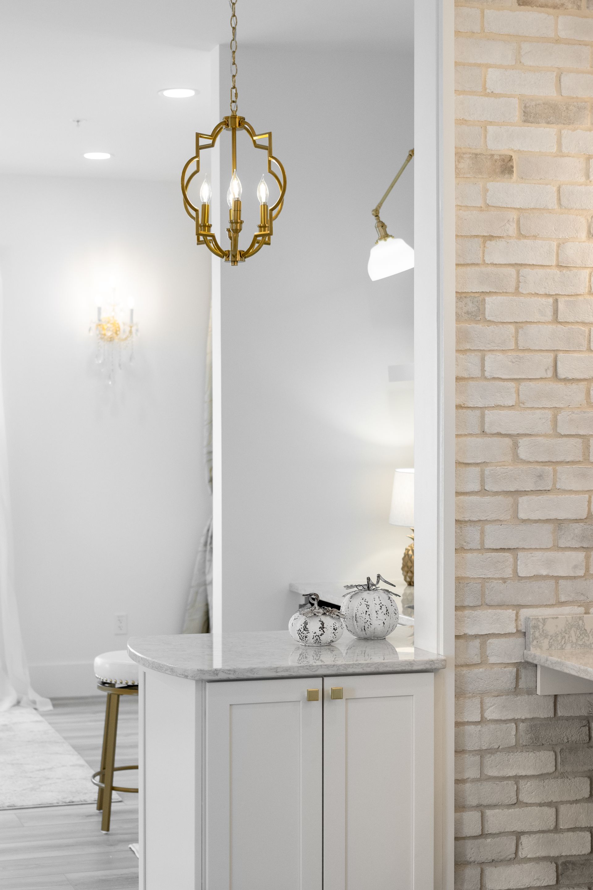 Modern vanity with gold pendant light beside white brick wall in a bright room