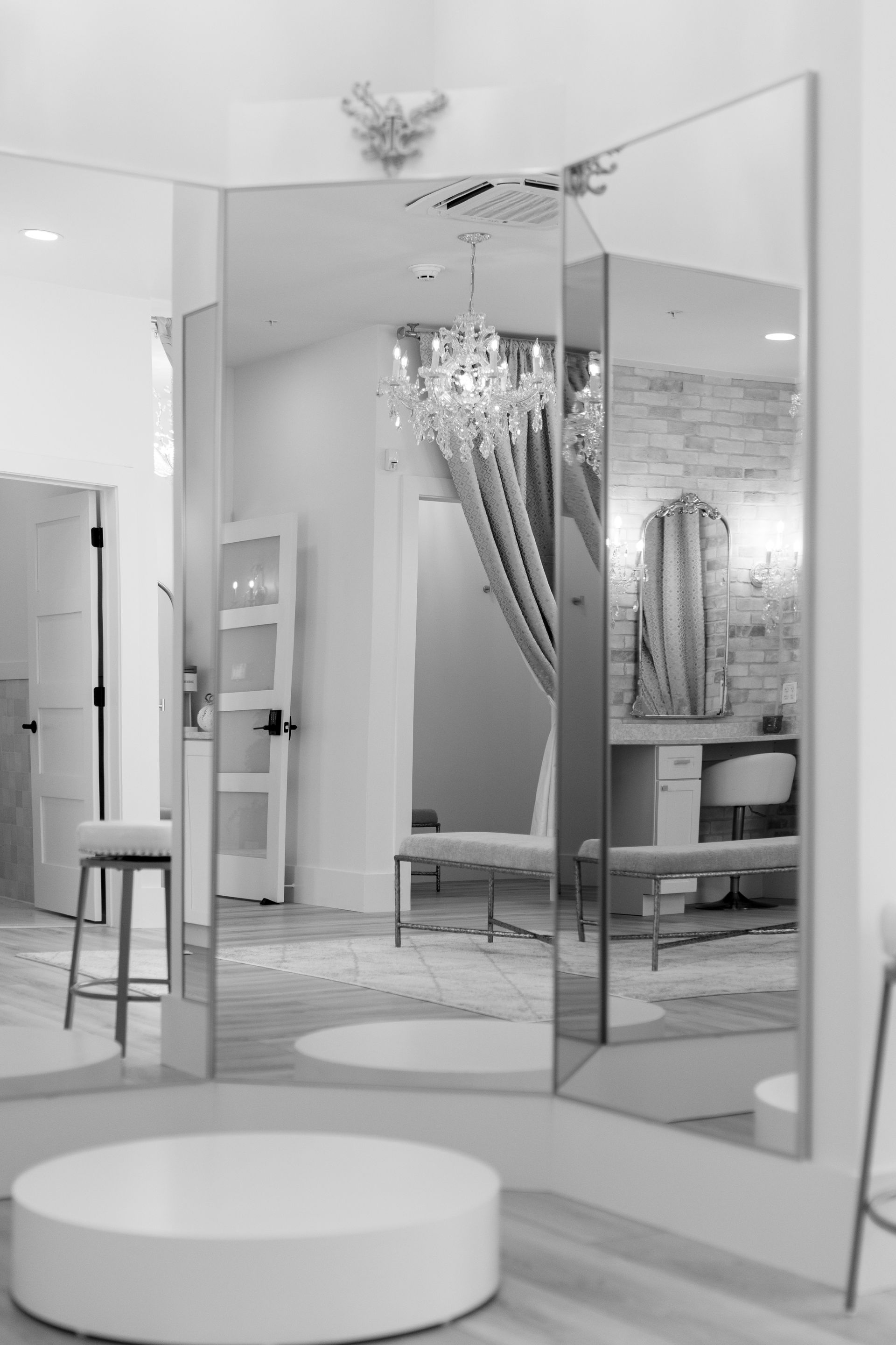 Modern white interior with mirrored panels, a stool, and a round bench