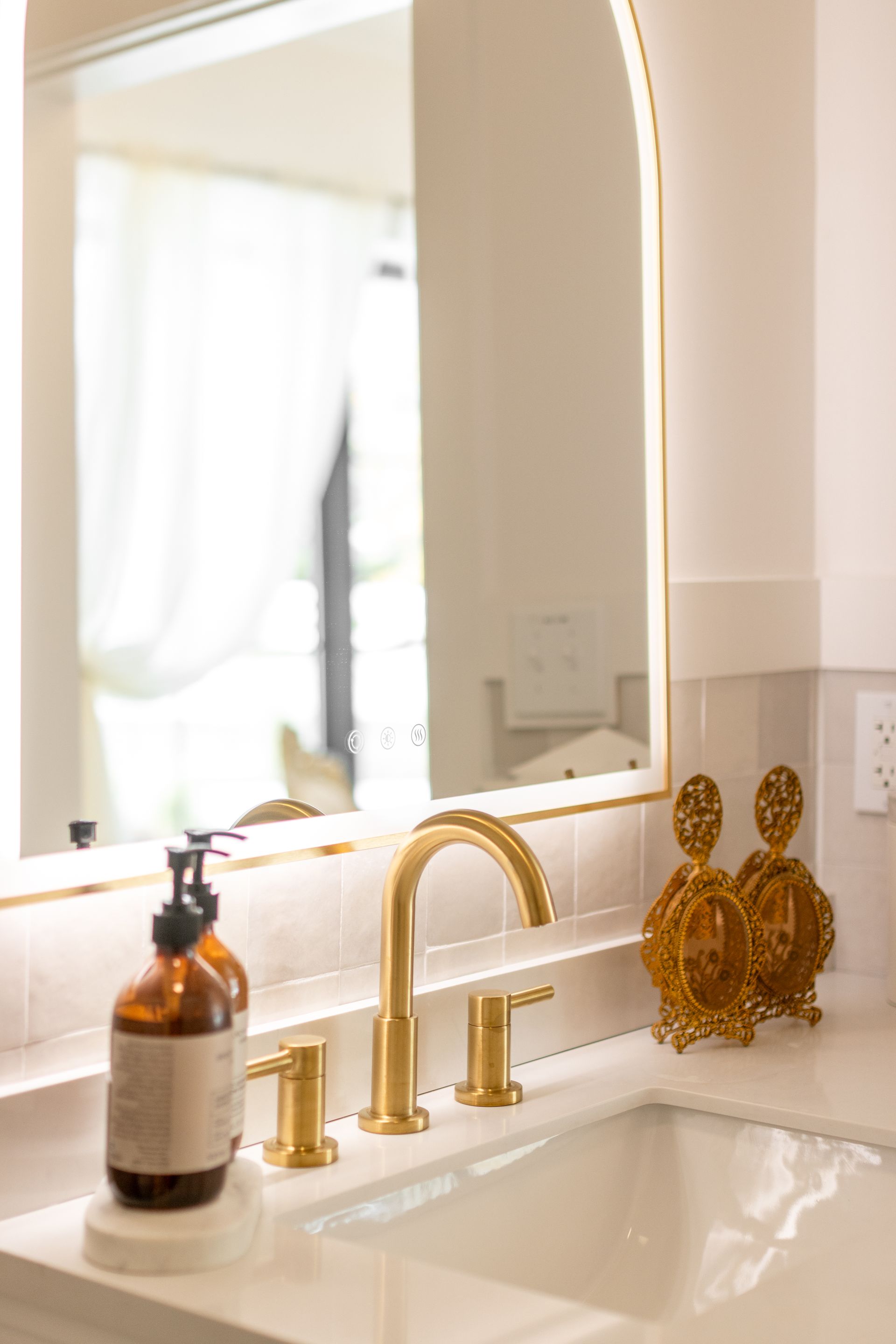 Bathroom vanity with gold faucet, mirror, soap dispenser, and decorative gold ornaments on the counter.