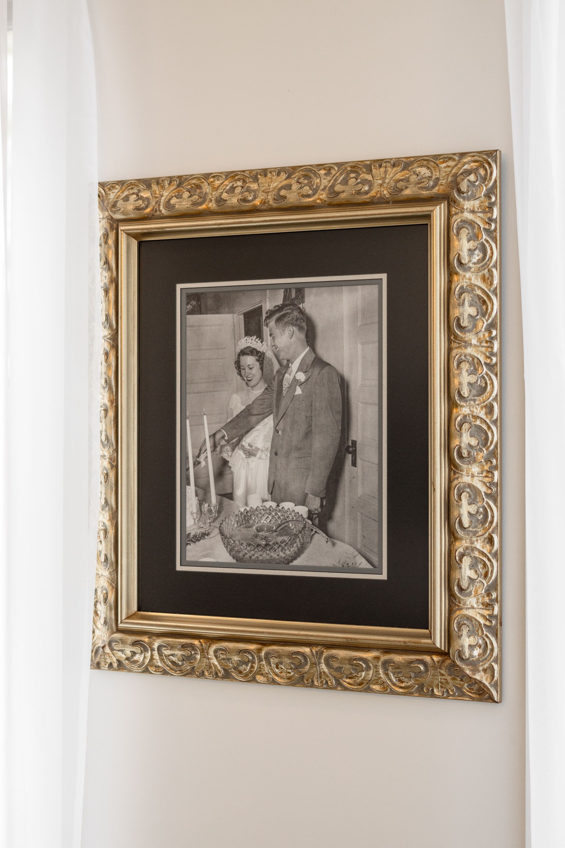 Framed black-and-white portrait with an ornate gold frame hanging on a white wall