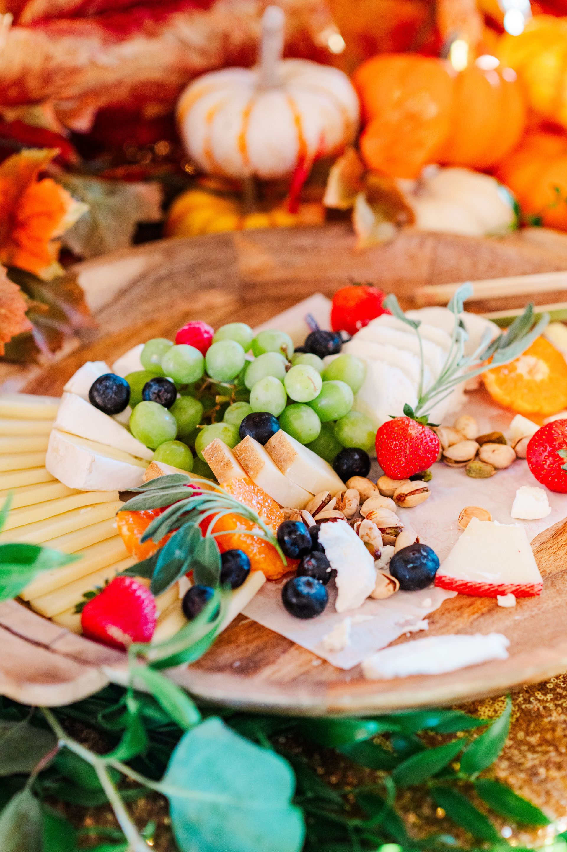 Fruit and cheese platter with grapes, berries, crackers, and pumpkin decor on a rustic table