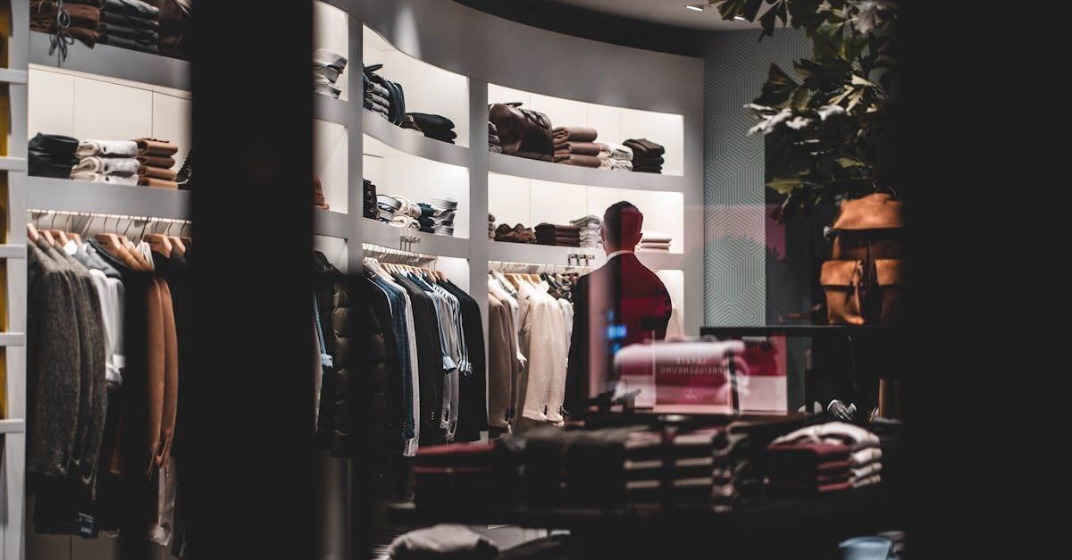A man is standing in a clothing store looking at clothes.