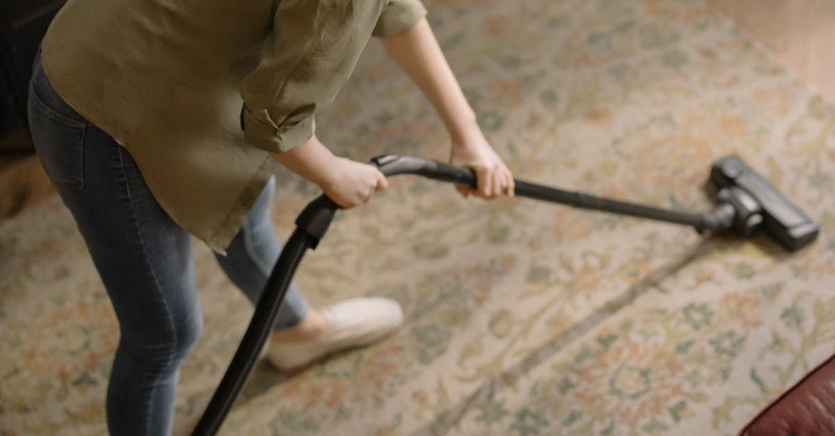 A woman is using a vacuum cleaner to clean a rug in a living room.