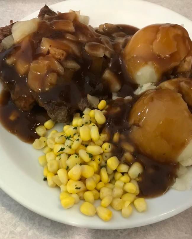 Plate of stew with two dumplings and corn kernels on the side