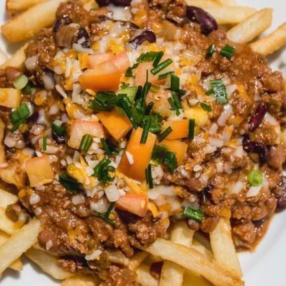 Loaded fries topped with chili, diced tomatoes, onions, and chopped chives