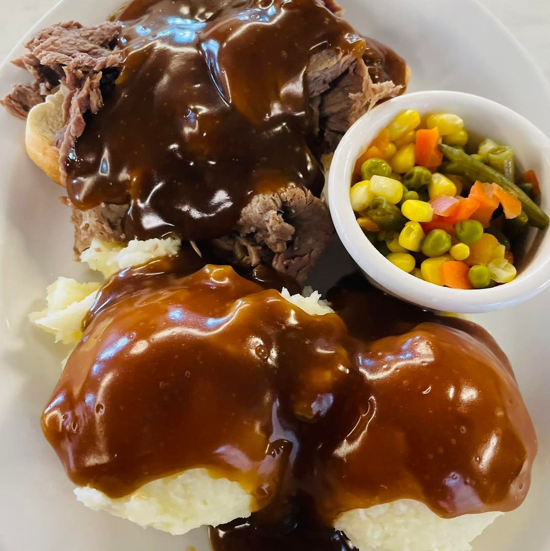 Pot roast with brown gravy, mashed potatoes, and mixed vegetables on a white plate