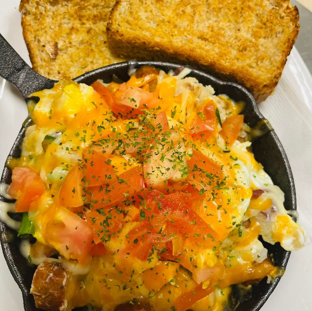 Skillet hash topped with tomatoes and herbs, served with toast on the side