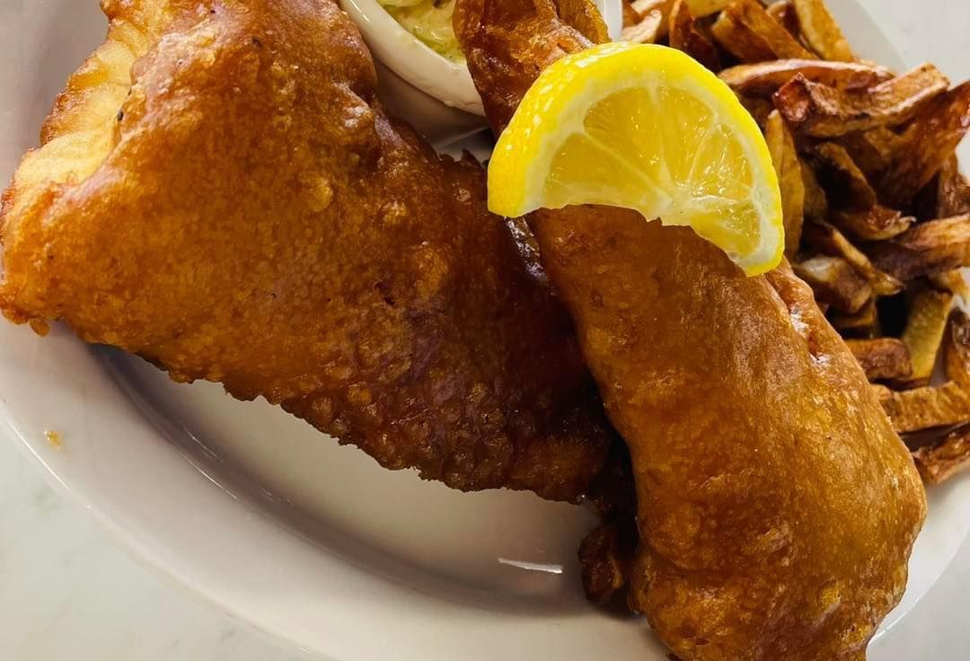 Fried fish fillets on a plate with lemon wedges and fries