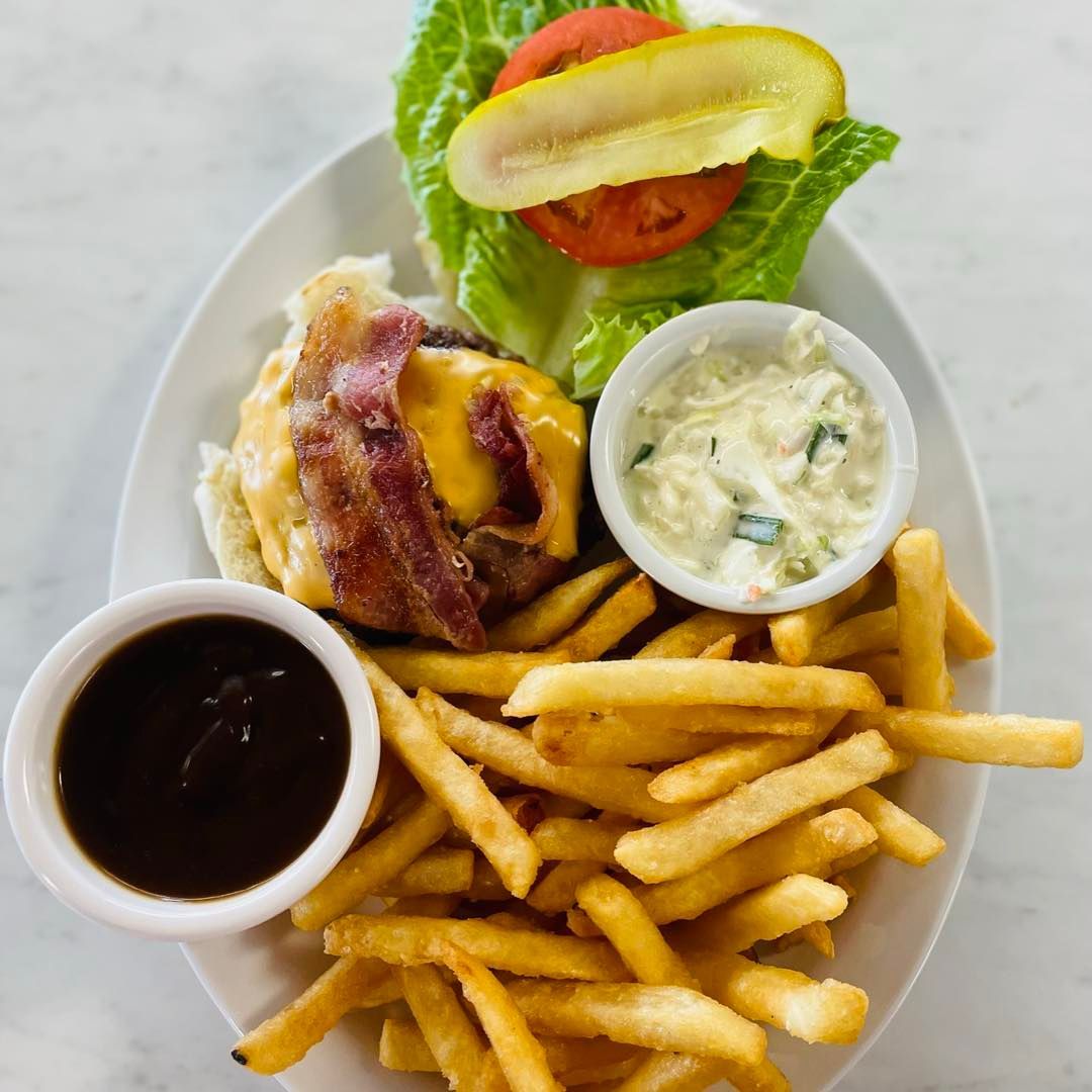 Plate of French fries with burger, coleslaw, tomato and lettuce, plus two dipping sauces