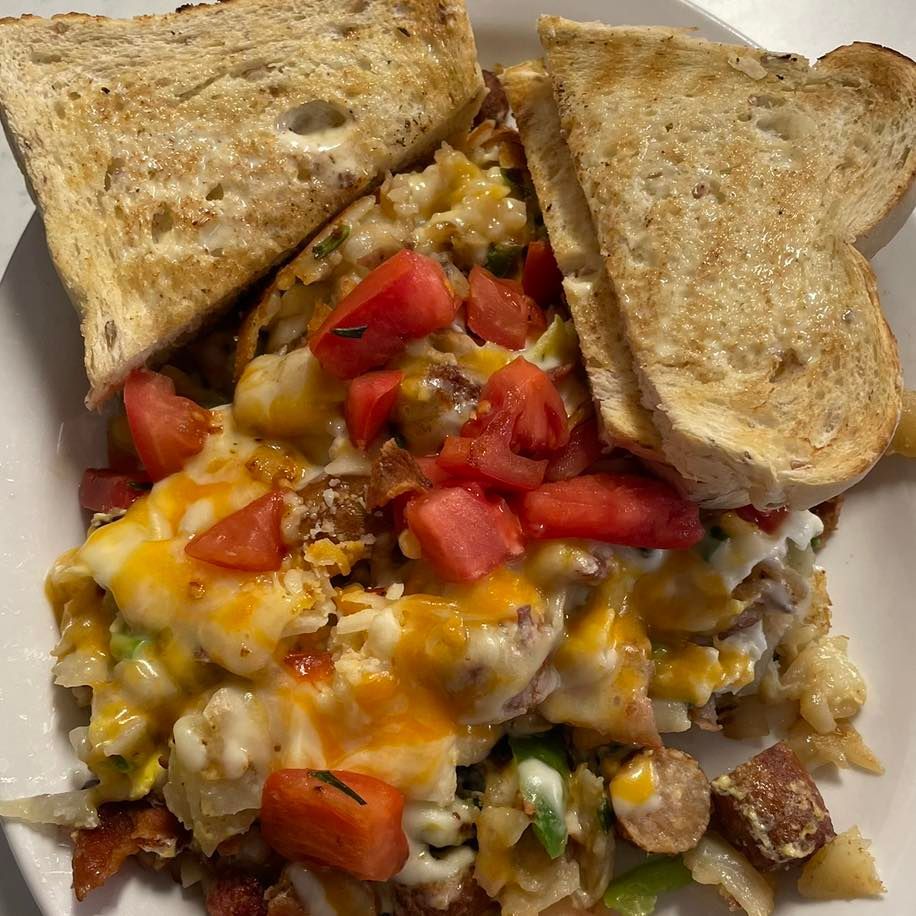 Open-faced sandwich topped with melted cheese, diced tomatoes, and toasted bread slices