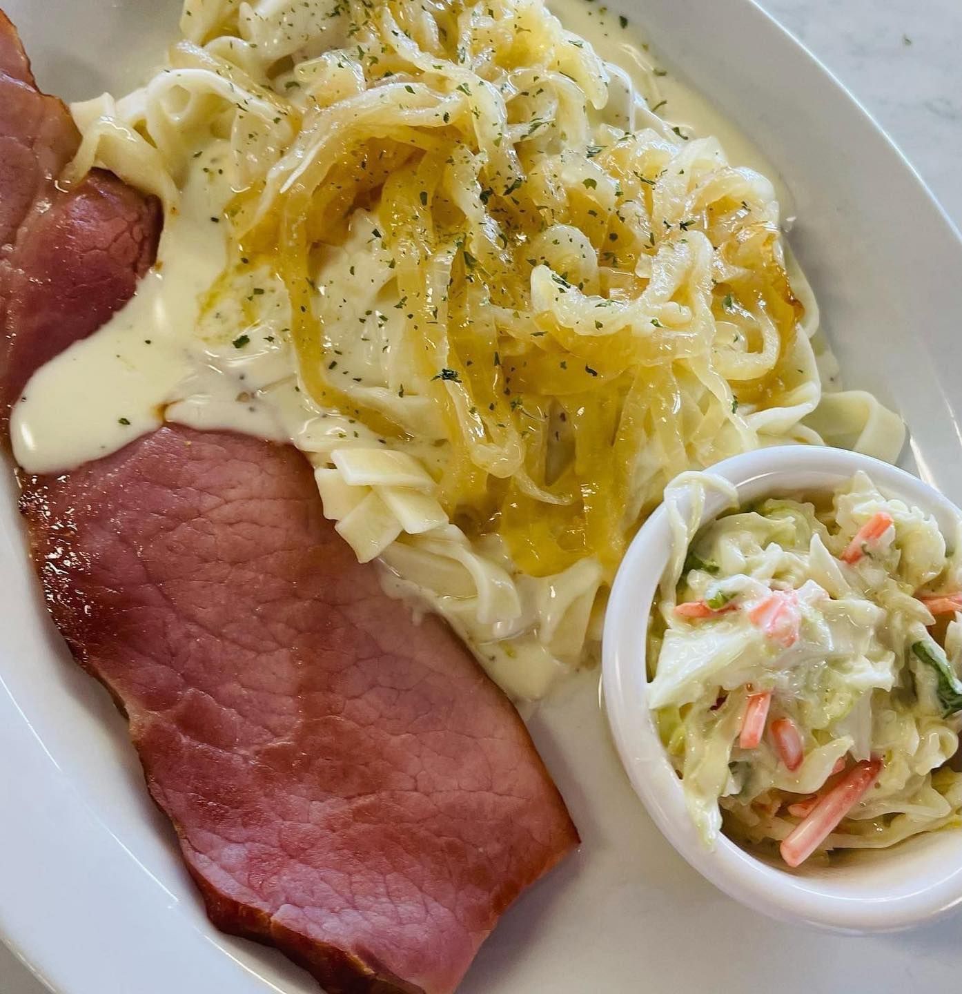 Plate with sliced roast beef, creamy noodles, and a small cup of coleslaw