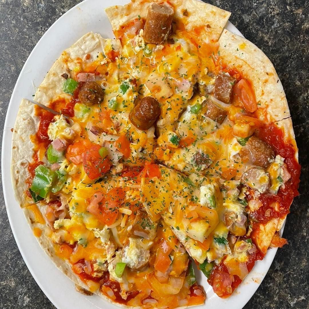 Top-down view of a cheesy pizza with pepperoni, vegetables, and herbs on a plate