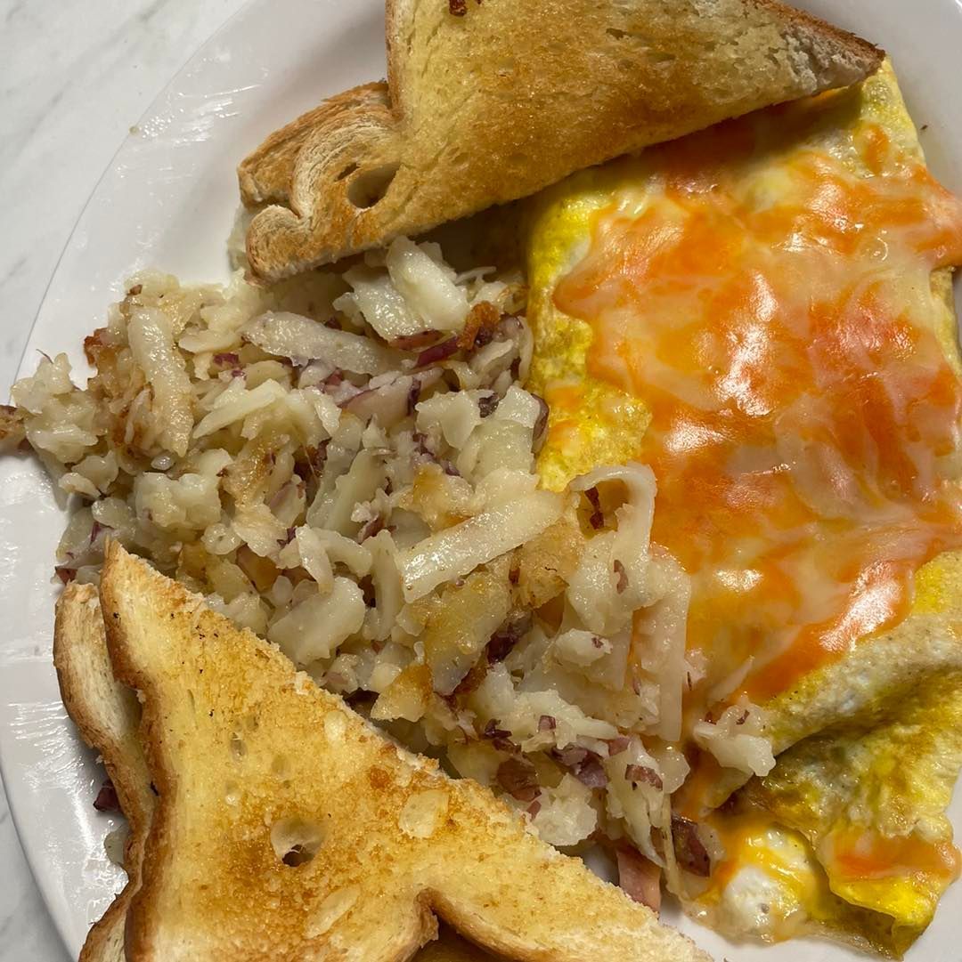 Plate of breakfast food with toast, hash browns, and an egg topped with melted cheese and salsa